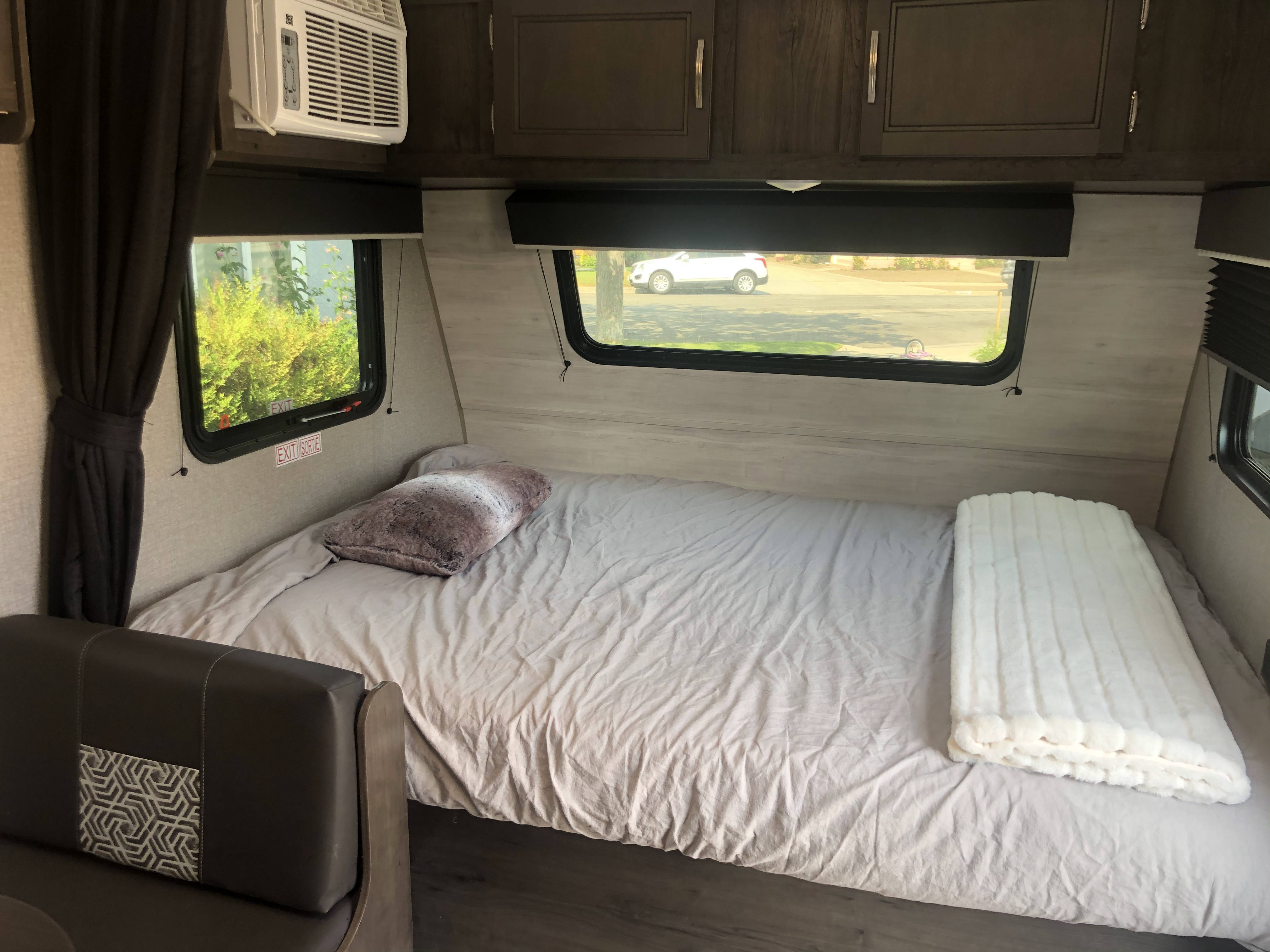 Experience a comfortable RV rental. This cozy interior features a bed, fluffy blanket, AC, and window views.. Jayco Jay Flight 2021