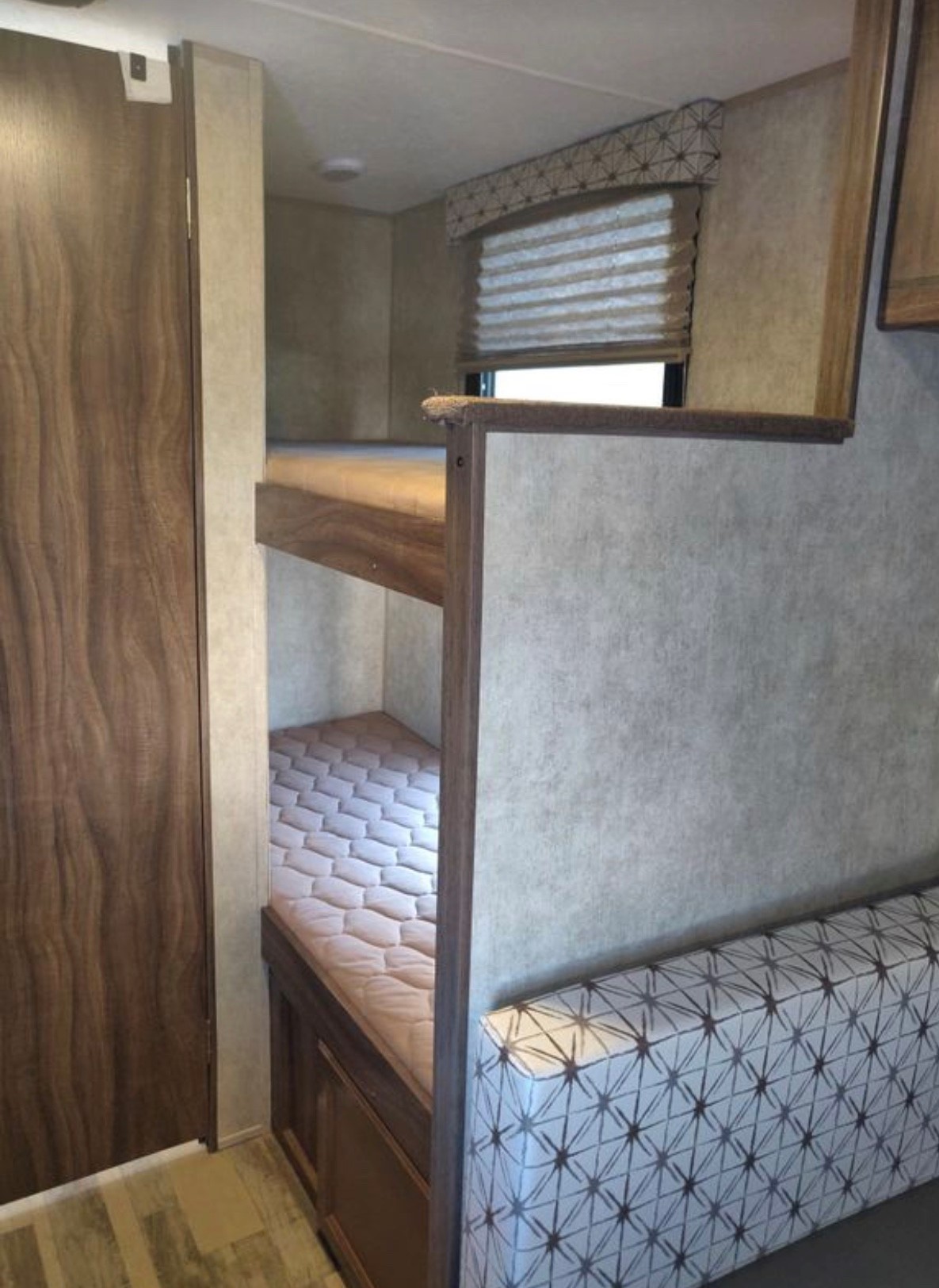 RV rental interior features bunk beds, a patterned sofa, and a door for compact living space.. Coachmen Viking 2017