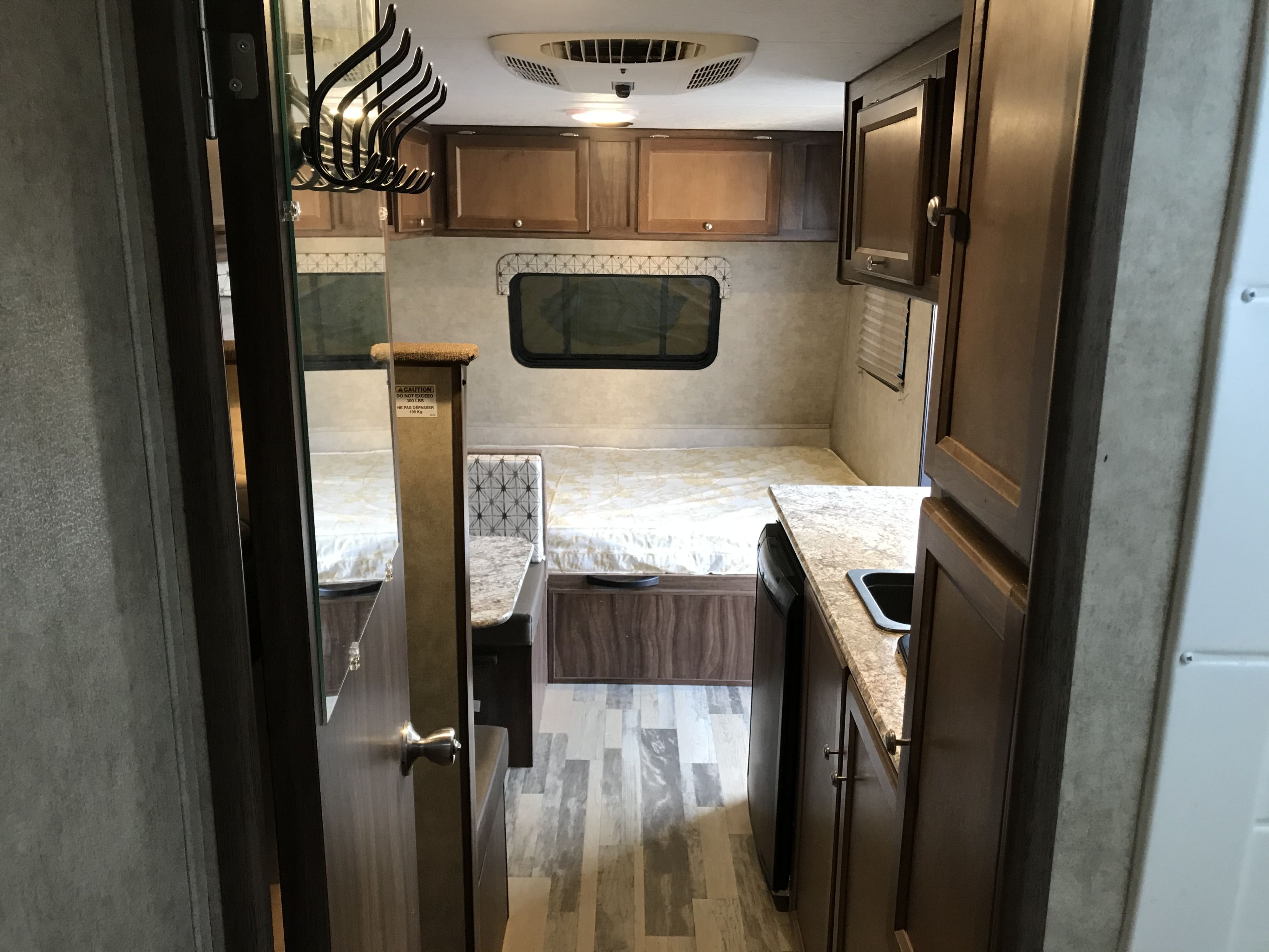 RV rental interior shows a compact living space: kitchen, dining area, bed, and overhead cabinets.. Coachmen Viking 2017