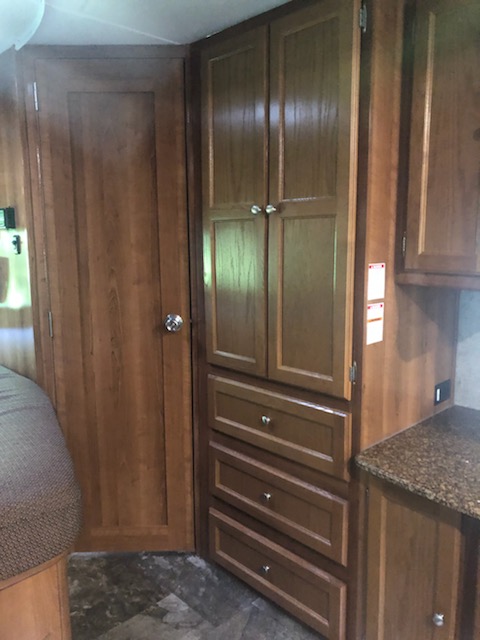 RV rental interior featuring wood cabinets, drawers, and a door, offering functional storage space.. Coachmen Leprechaun 2018