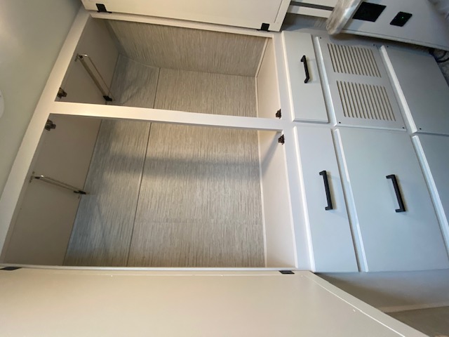 RV rental interior showing an ample open closet with textured walls & shelves, beside sleek white cabinets with black pulls.. Thor Motor Coach Chateau 2021