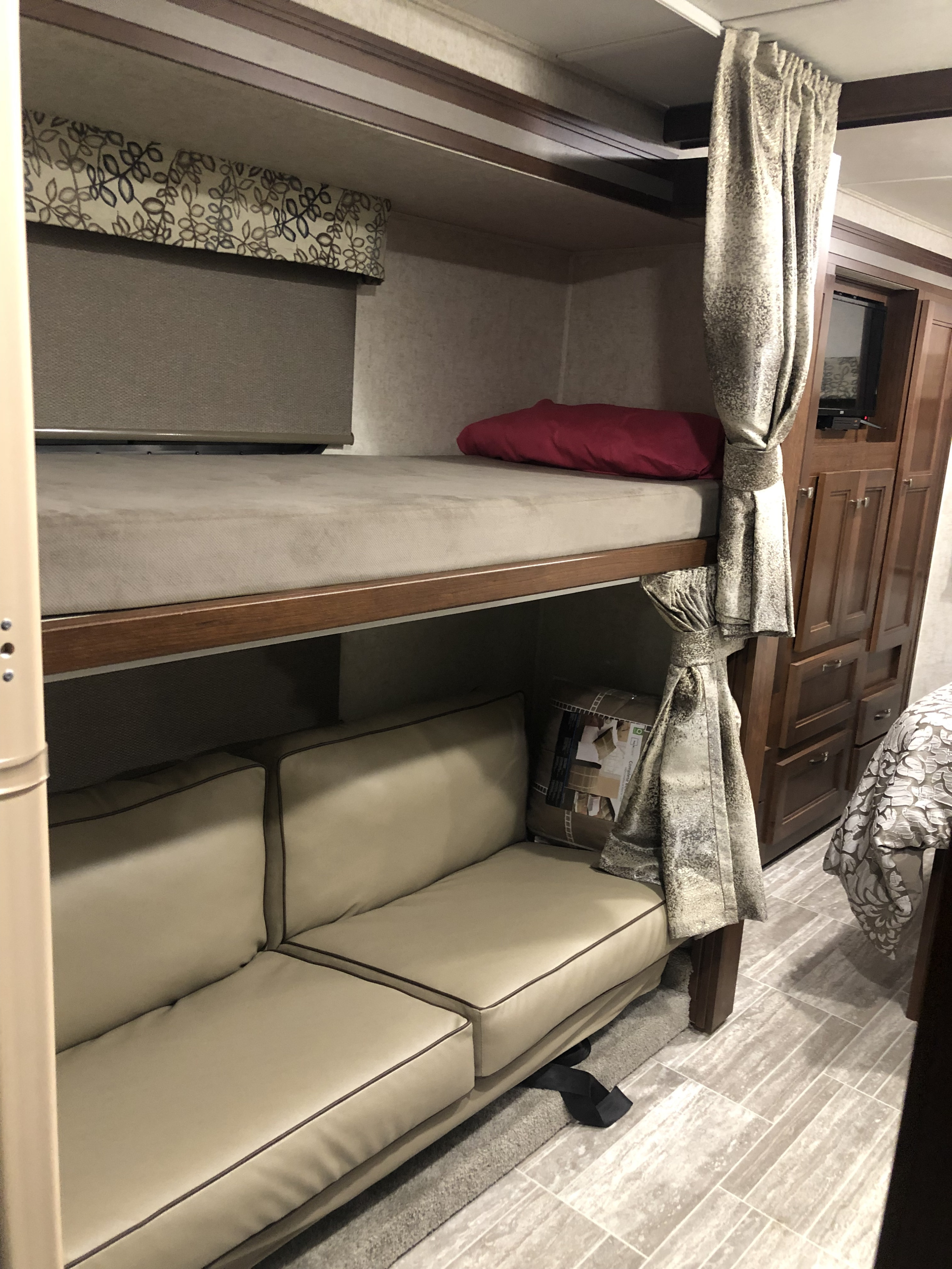 RV rental interior: bunk beds, a beige sofa below, wood cabinetry with TV, and patterned curtains. Great for travel!. Forest River forester 2019