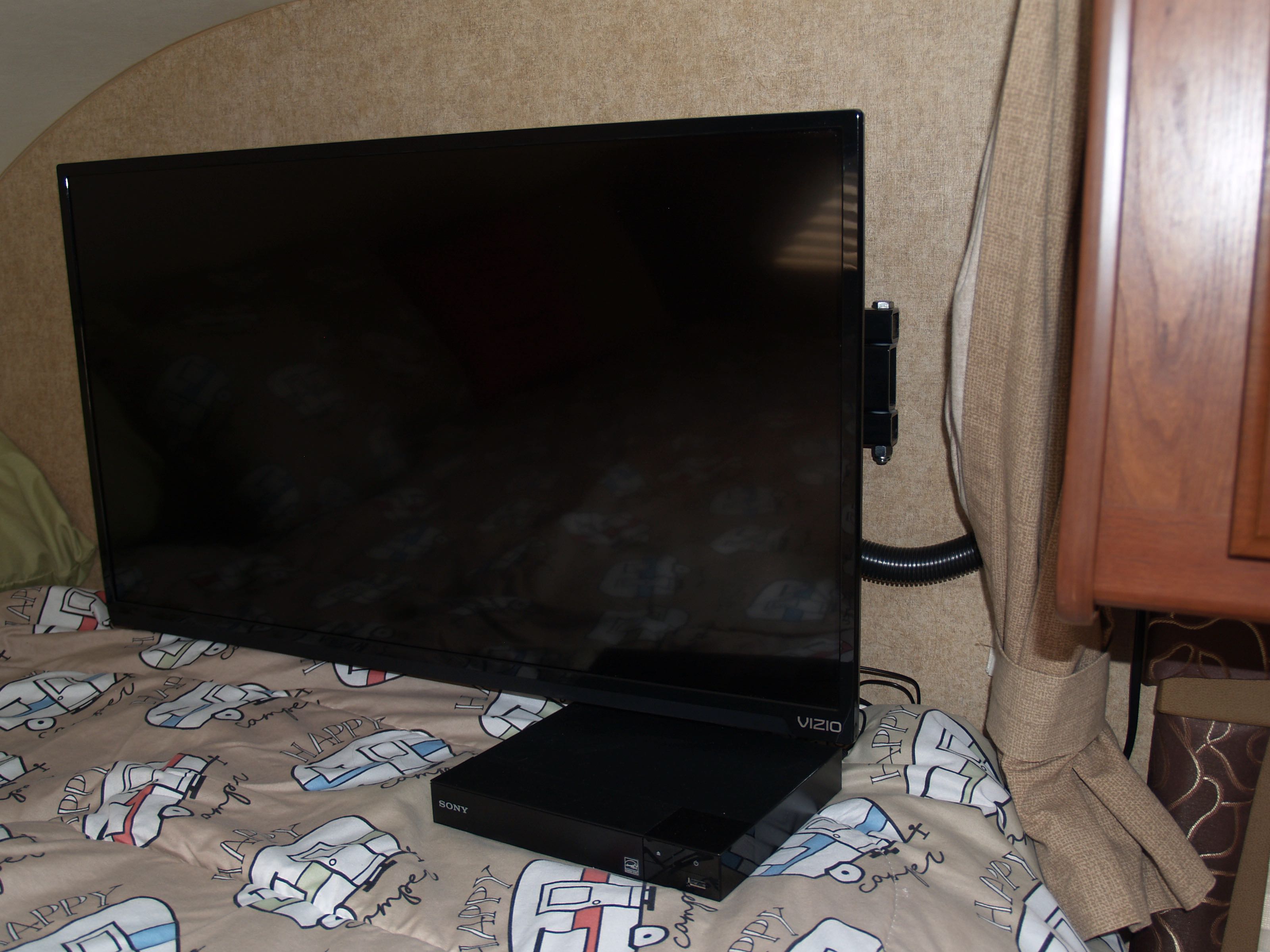 Vizio TV and Sony Blu-ray player on 'Happy Camper' bedding in an RV rental interior.. Thor Motor Coach Chateau 2014