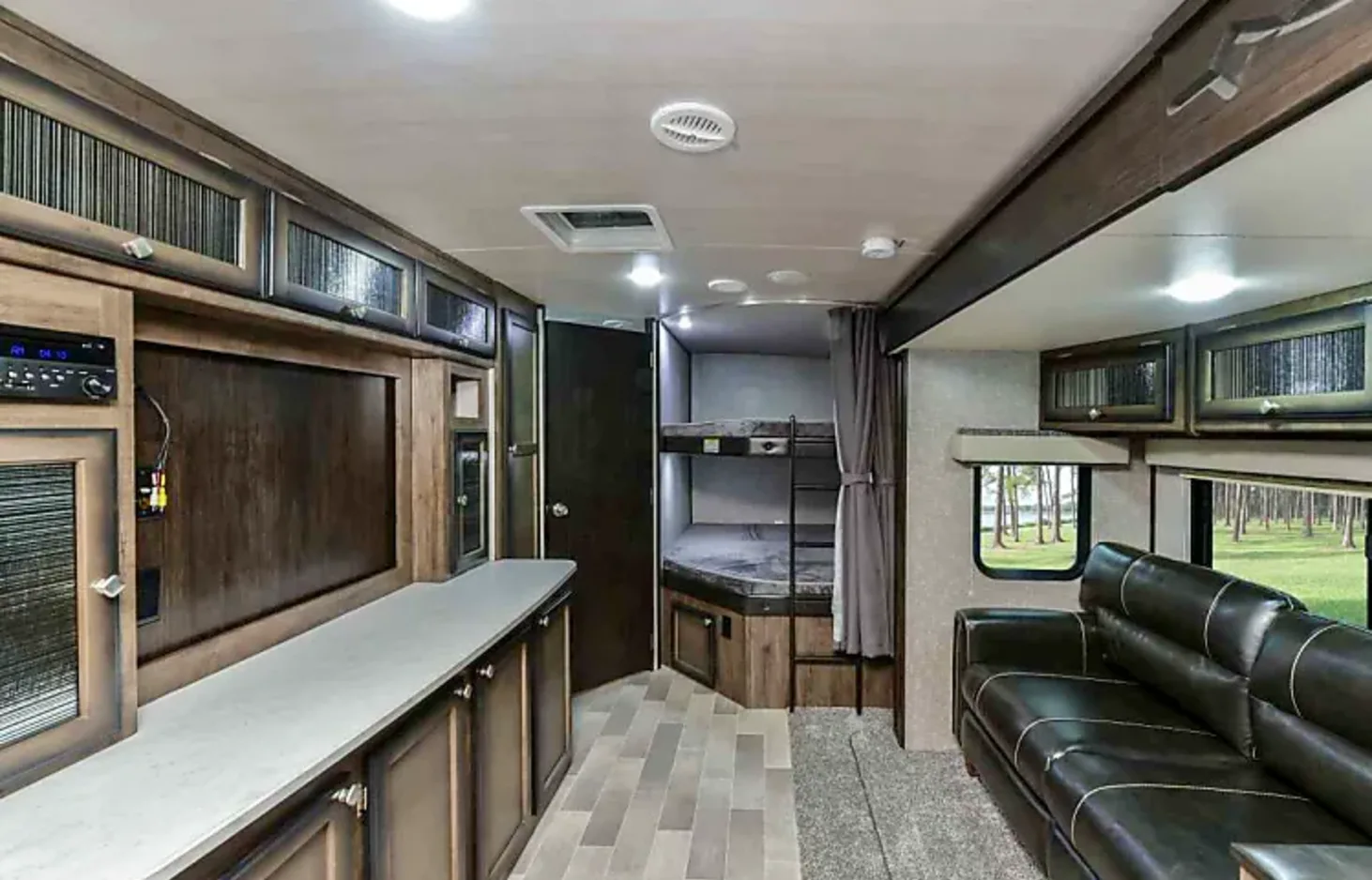 This RV rental interior features a cozy living area with a couch, entertainment center, and private bunk beds, ideal for family travel.. Heartland RVs Mallard 2019