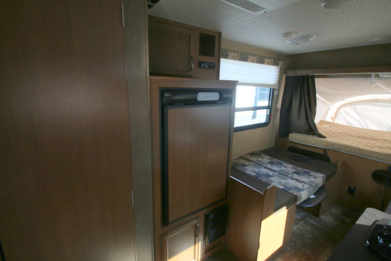 RV rental interior featuring a refrigerator, dining area with patterned cushions, and a cozy pop-out bed.. Starcraft Launch 2014