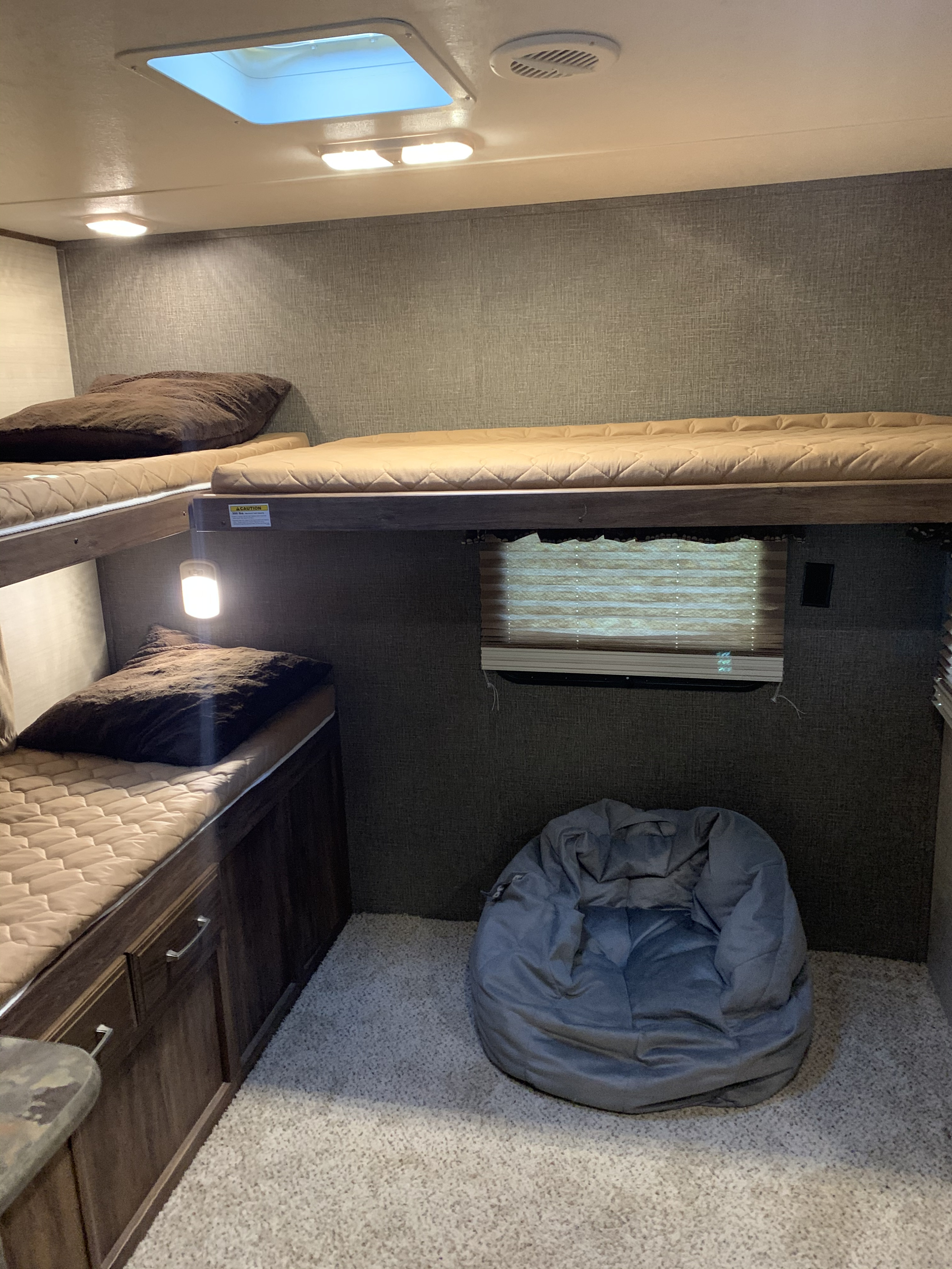 RV rental bunk bed area: two cozy bunks, a grey bean bag, carpeted floor, and skylight in a compact camper interior.. Keystone Cougar 31SQBWE 2015