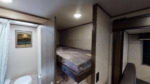 This RV rental offers a compact bathroom, cozy bunk beds, and a glimpse of the living space. Perfect for your next road trip adventure!. Jayco 184BS 2021
