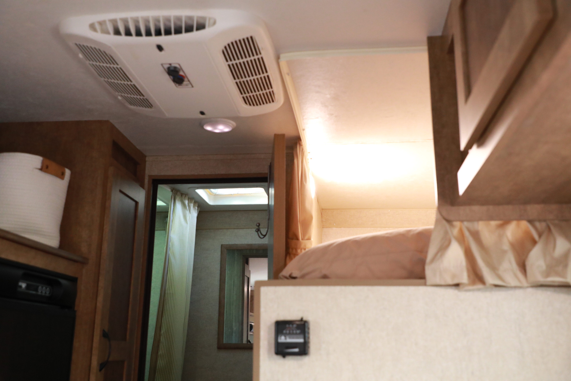 An RV rental interior with a ceiling AC unit, bright overhead bed, compact kitchen area, and a glimpse into the bathroom.. Starcraft Launch 2017