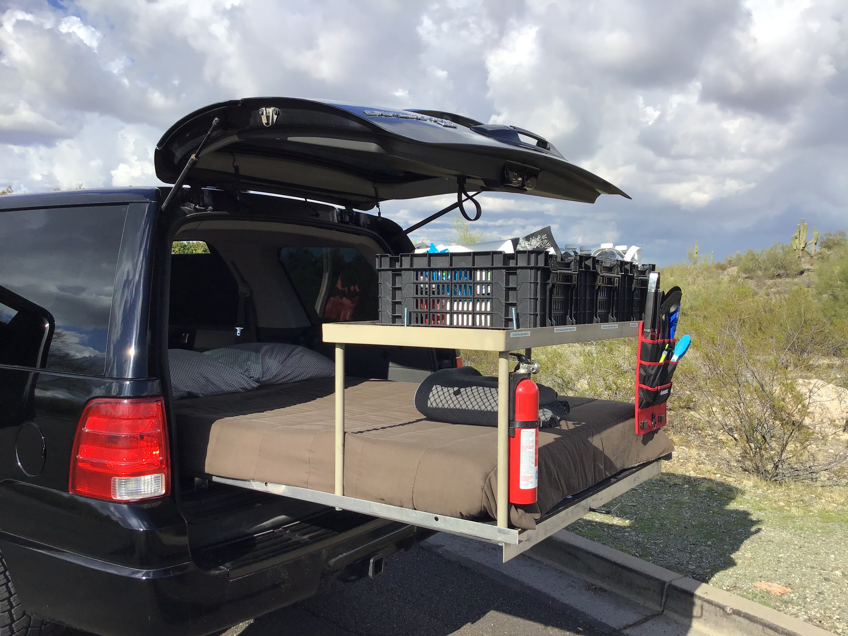 Black SUV with custom car camping setup, including a pull-out bed and overhead storage. An ideal RV rental alternative for desert adventures.. Ford Expedition Overland Campervan Conversion 2003
