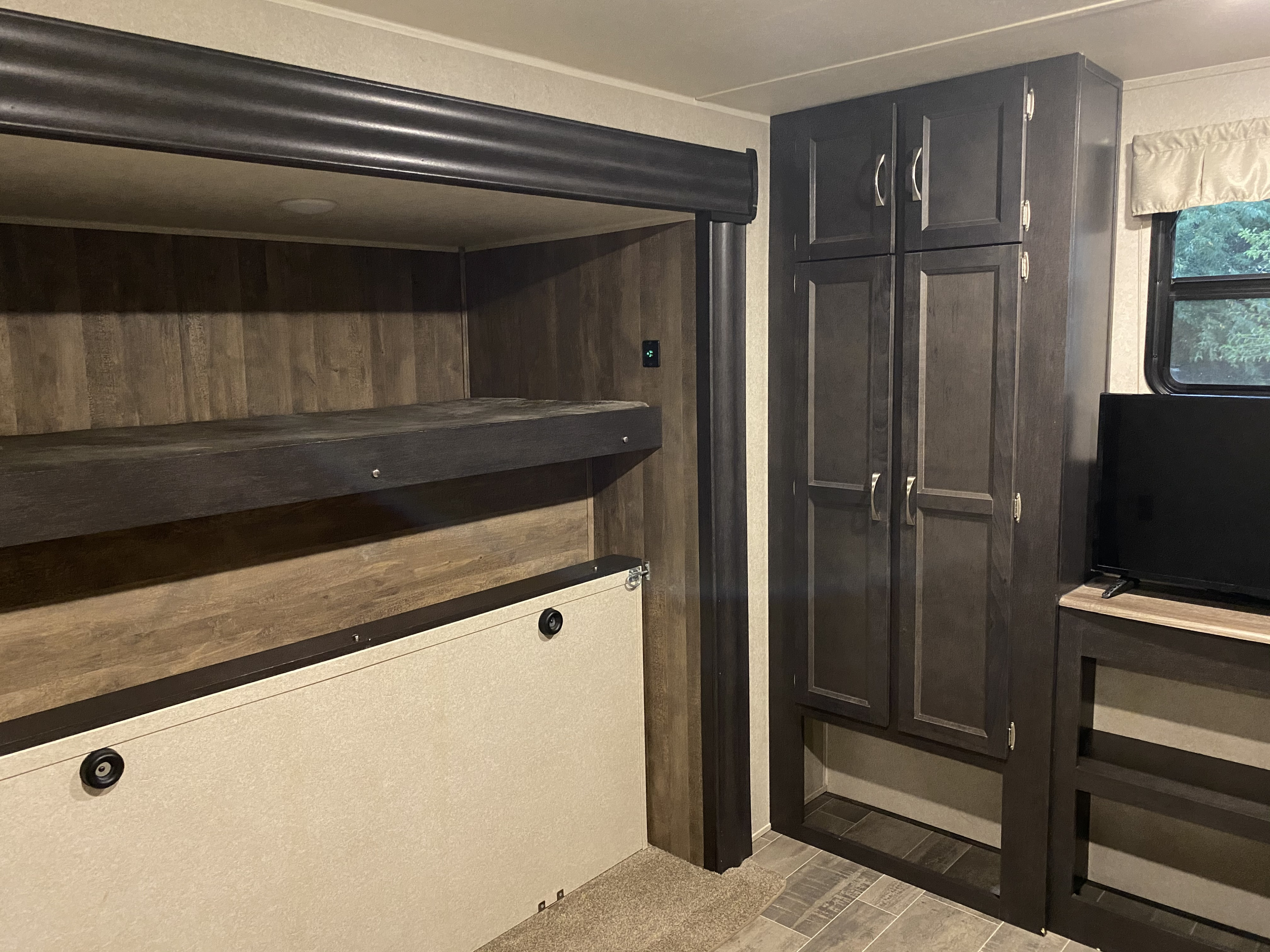 RV rental interior: bunk bed setup (lower folds up), dark storage cabinets, and a TV area.. Palomino Puma 2018