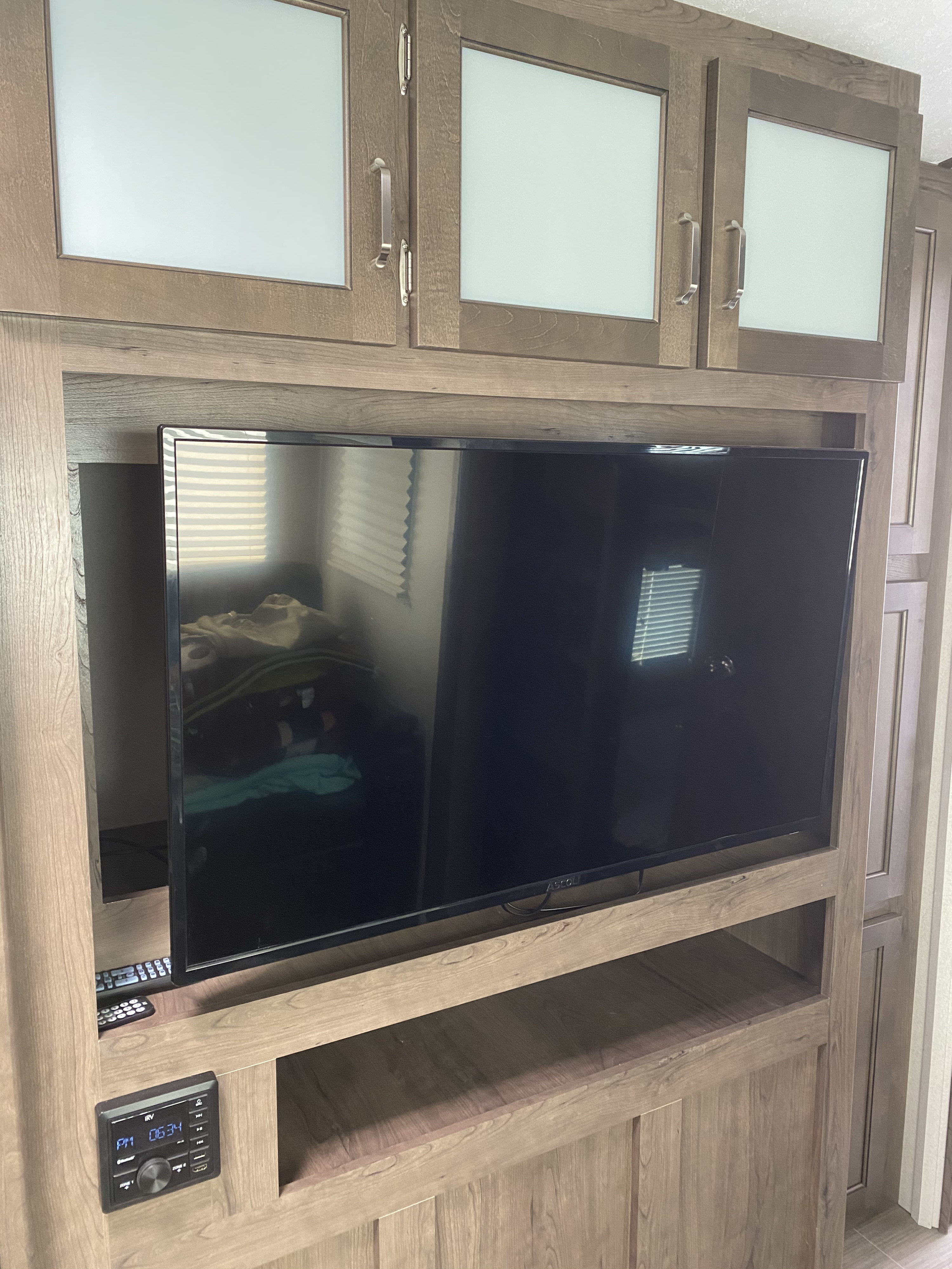 RV rental interior: Detailed view of a wood entertainment center with frosted glass cabinets, TV, and an RV media console.. Keystone RV Passport GT 2021