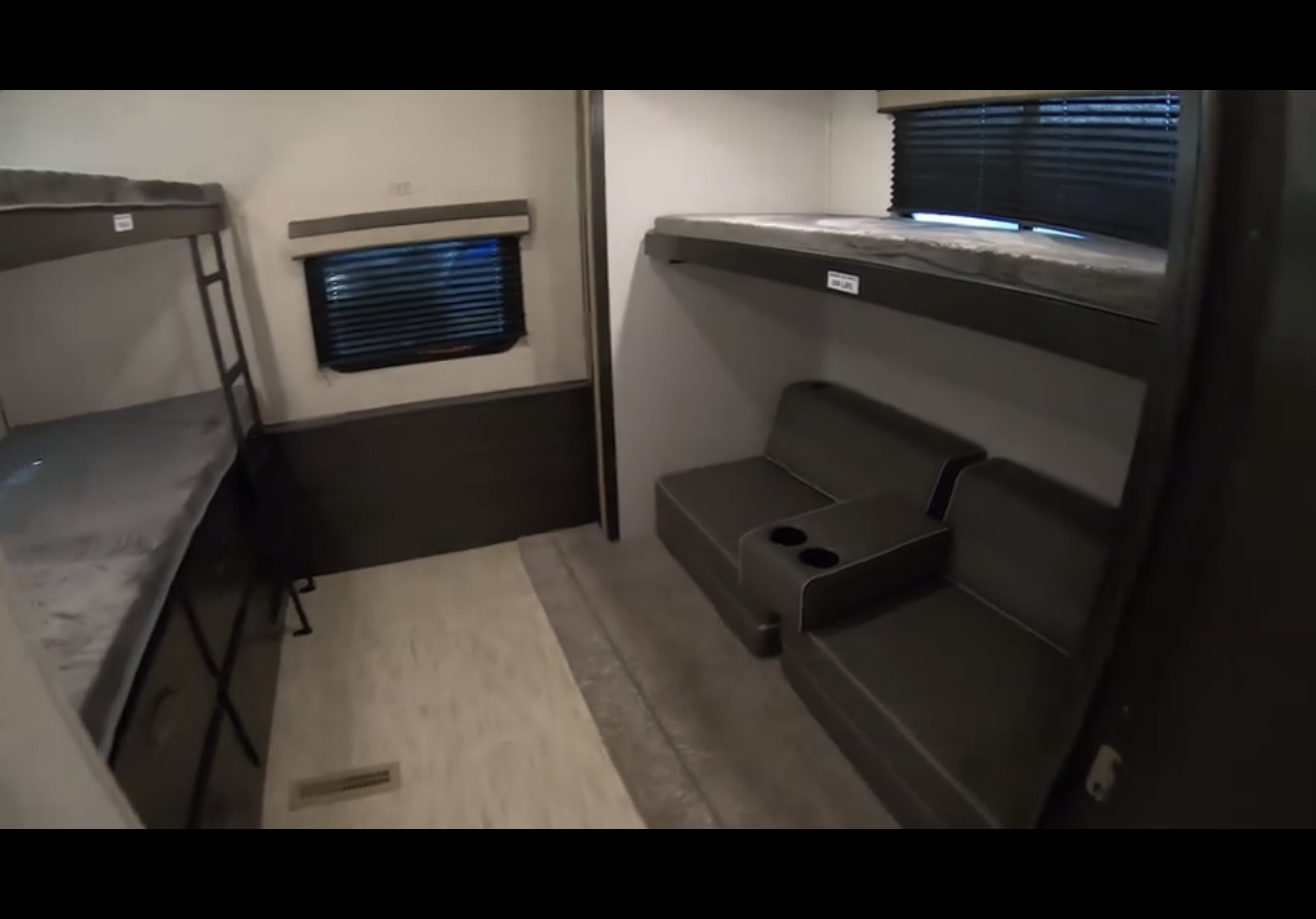 Inside an RV rental, a bunk room features two bunk beds and a comfortable seating area with cup holders, perfect for groups.. Forest River Surveyor Legend 2020
