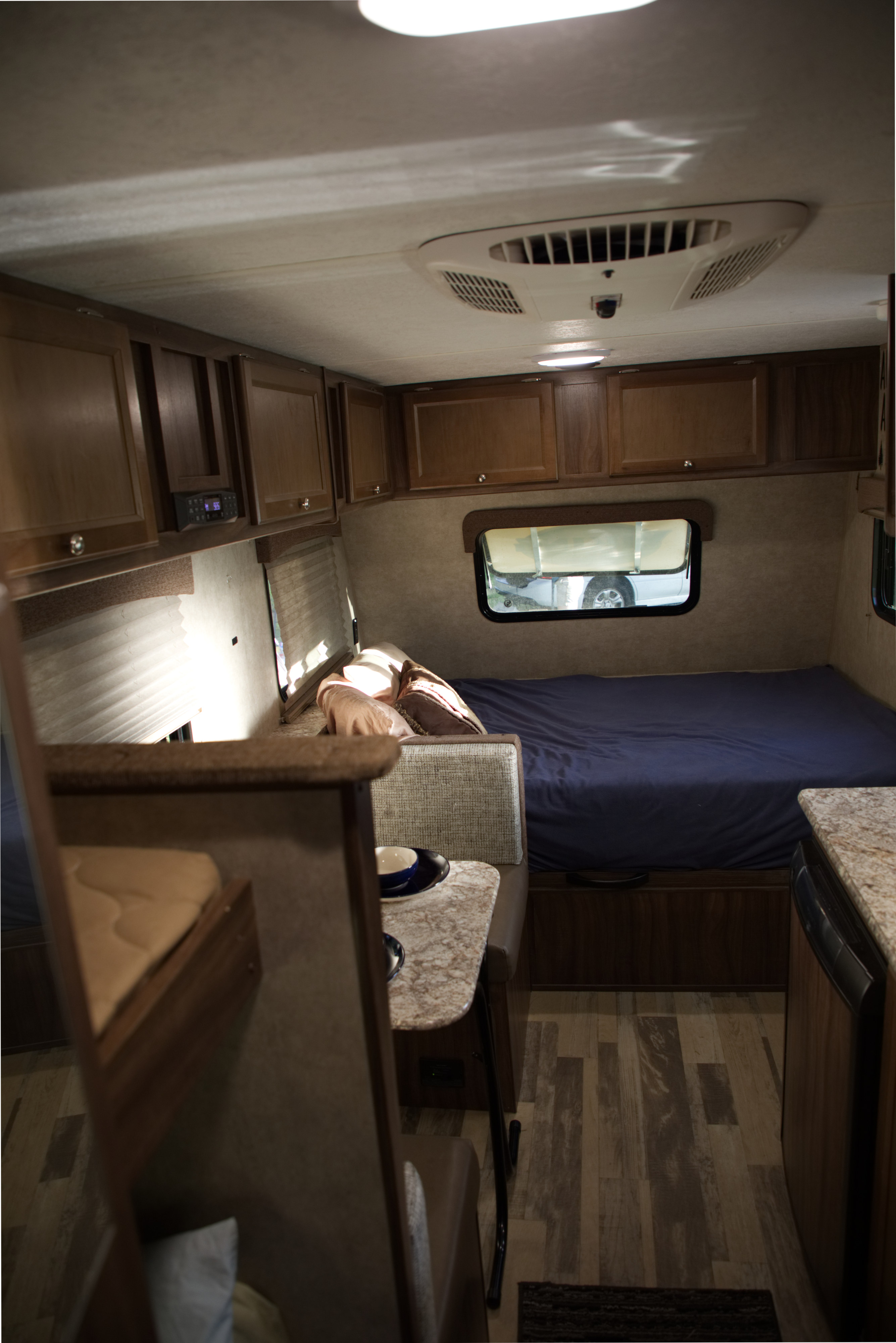 A cozy RV rental interior shows a blue-sheeted bed, dinette, and wood-toned cabinets, offering comfort on the go.. Forest River Other 2018