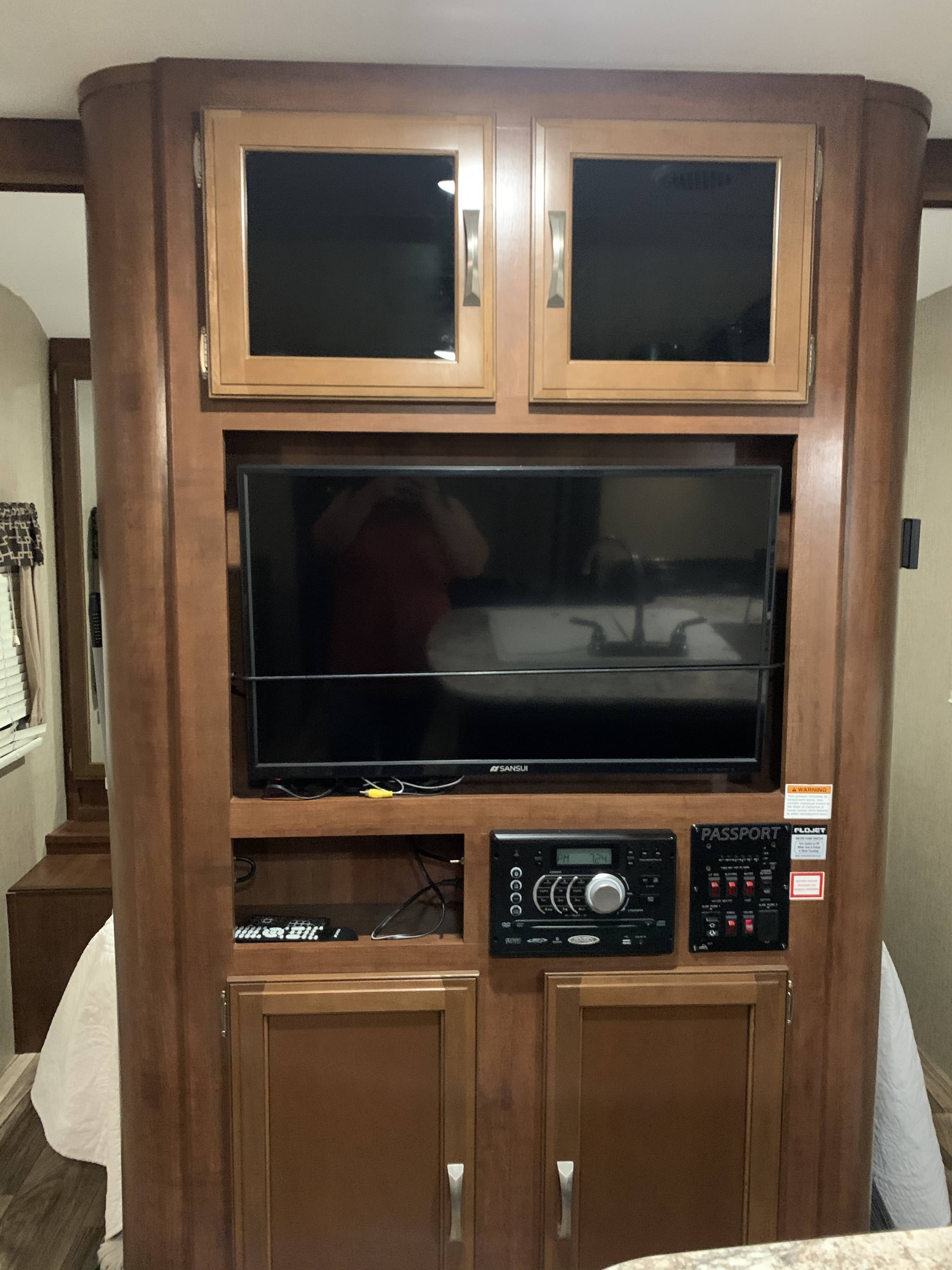 RV rental: Wooden entertainment center with TV, stereo, and RV control panel. Includes storage cabinets for your travels.. Keystone RV Passport Elite 2017