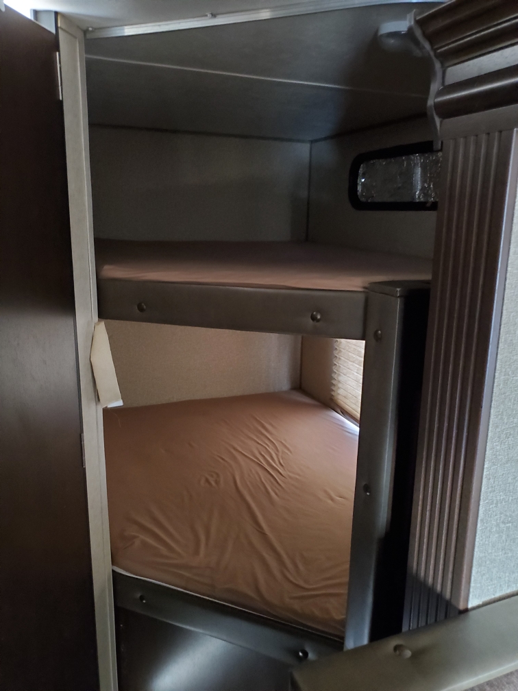 Interior view of an RV rental featuring two stacked bunk beds with light brown mattresses, offering compact sleeping space.. Forest River Cherokee Grey Wolf 2016