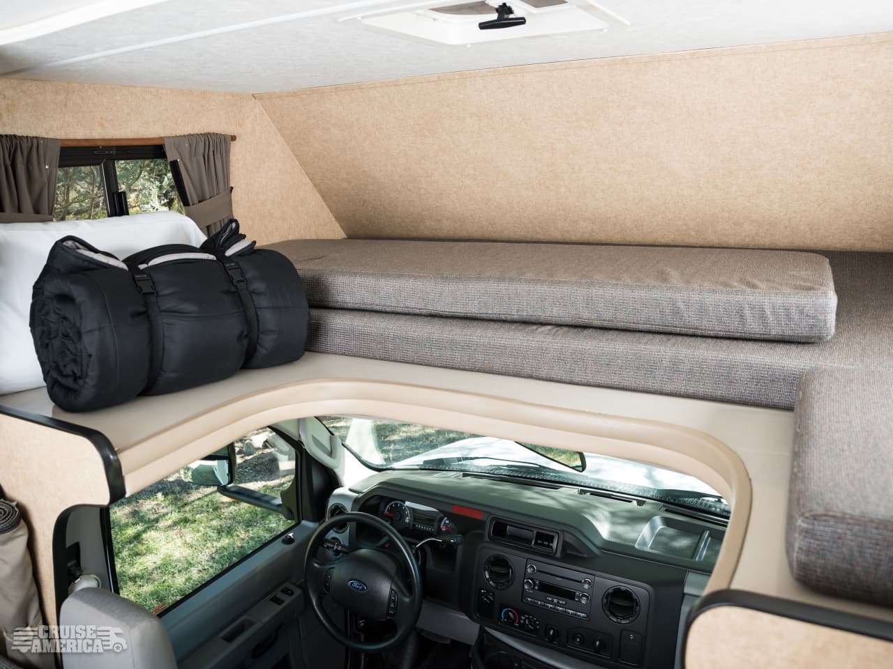 RV rental interior: a compact sleeping area with a rolled sleeping bag in the cab-over bunk, above the vehicle's cockpit.. Thor Motor Coach Four Winds Majestic 2017