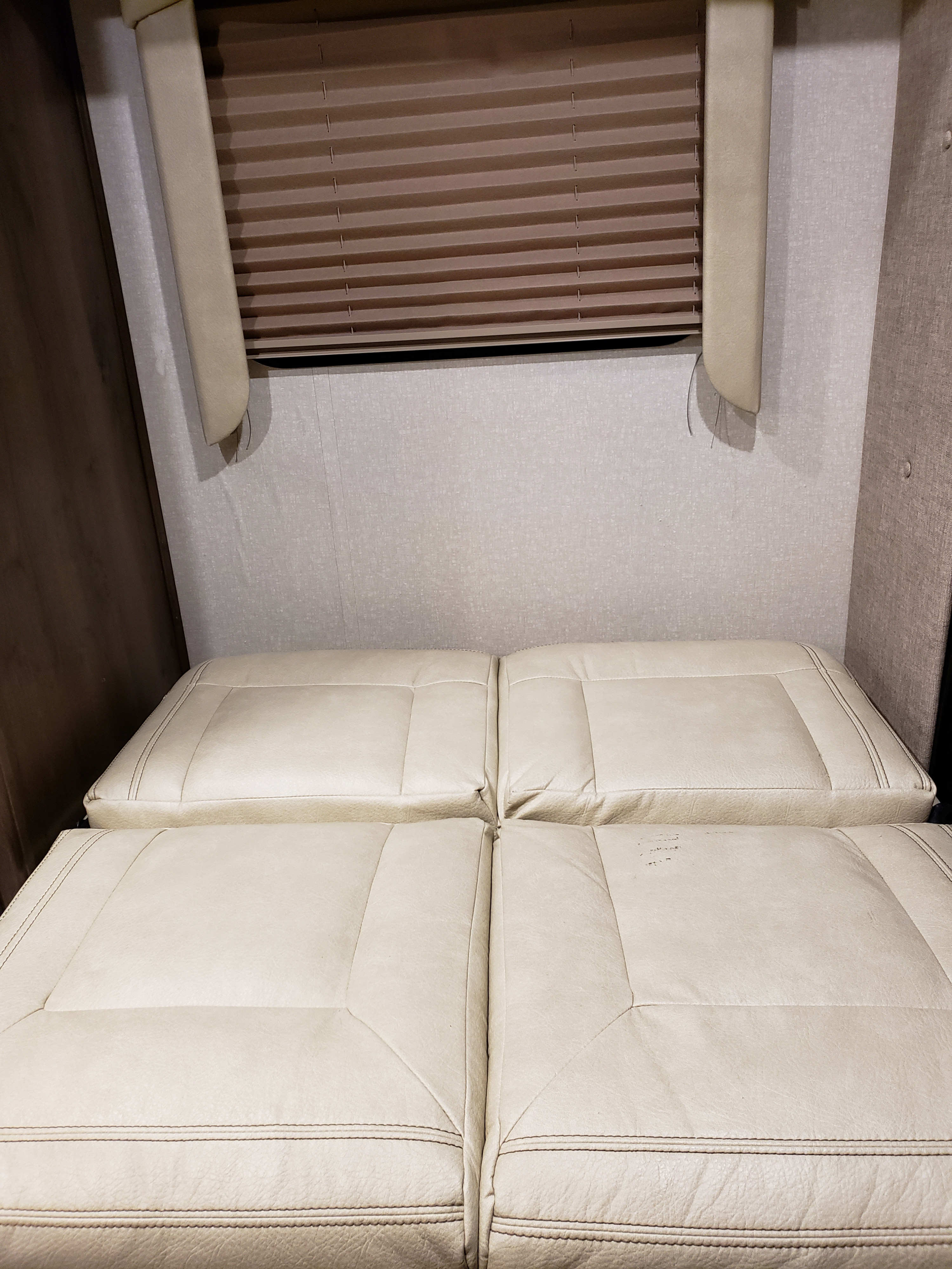 RV rental interior: Light beige cushions form a bed under a brown pleated blind in a compact space.. Coachmen Other 2018