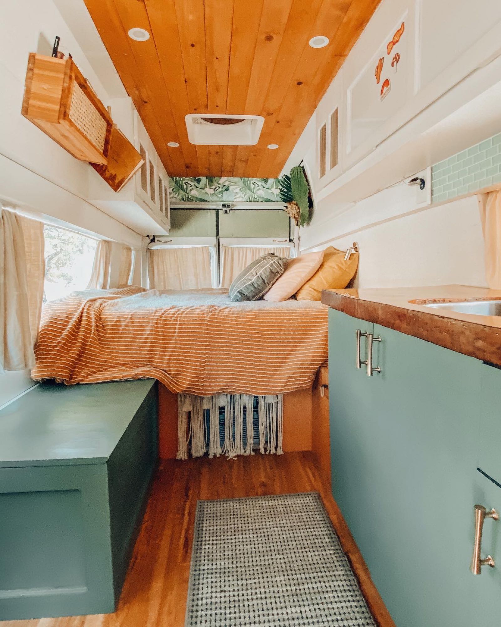 Stylish RV rental interior with cozy bed, green kitchenette, and warm wood accents.. Ford E150 Chariot Hi-Top Conversion 2009