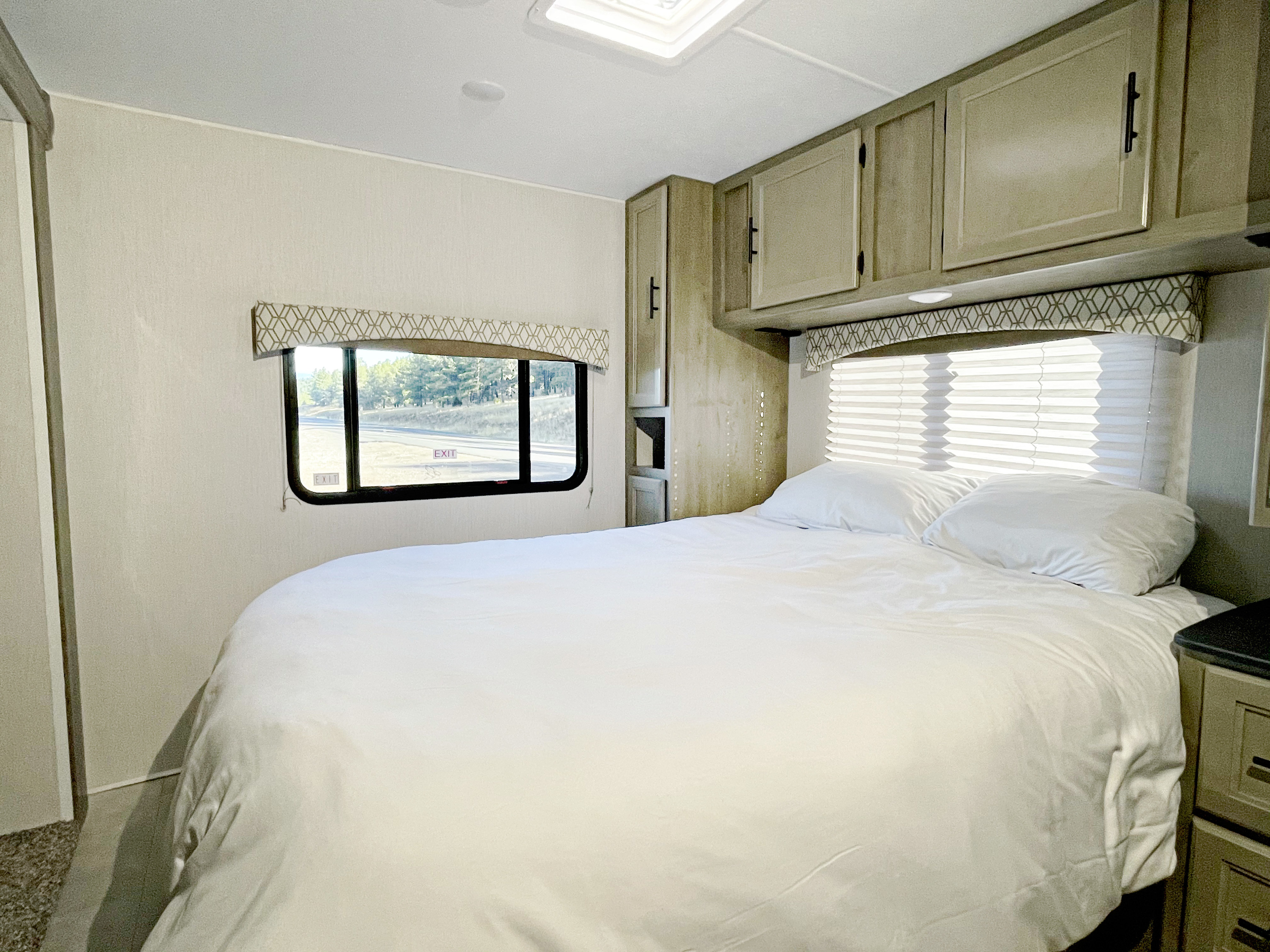This inviting RV rental bedroom offers a comfortable bed, smart storage, and a large window for scenic views.. Coachmen Freelander 2021