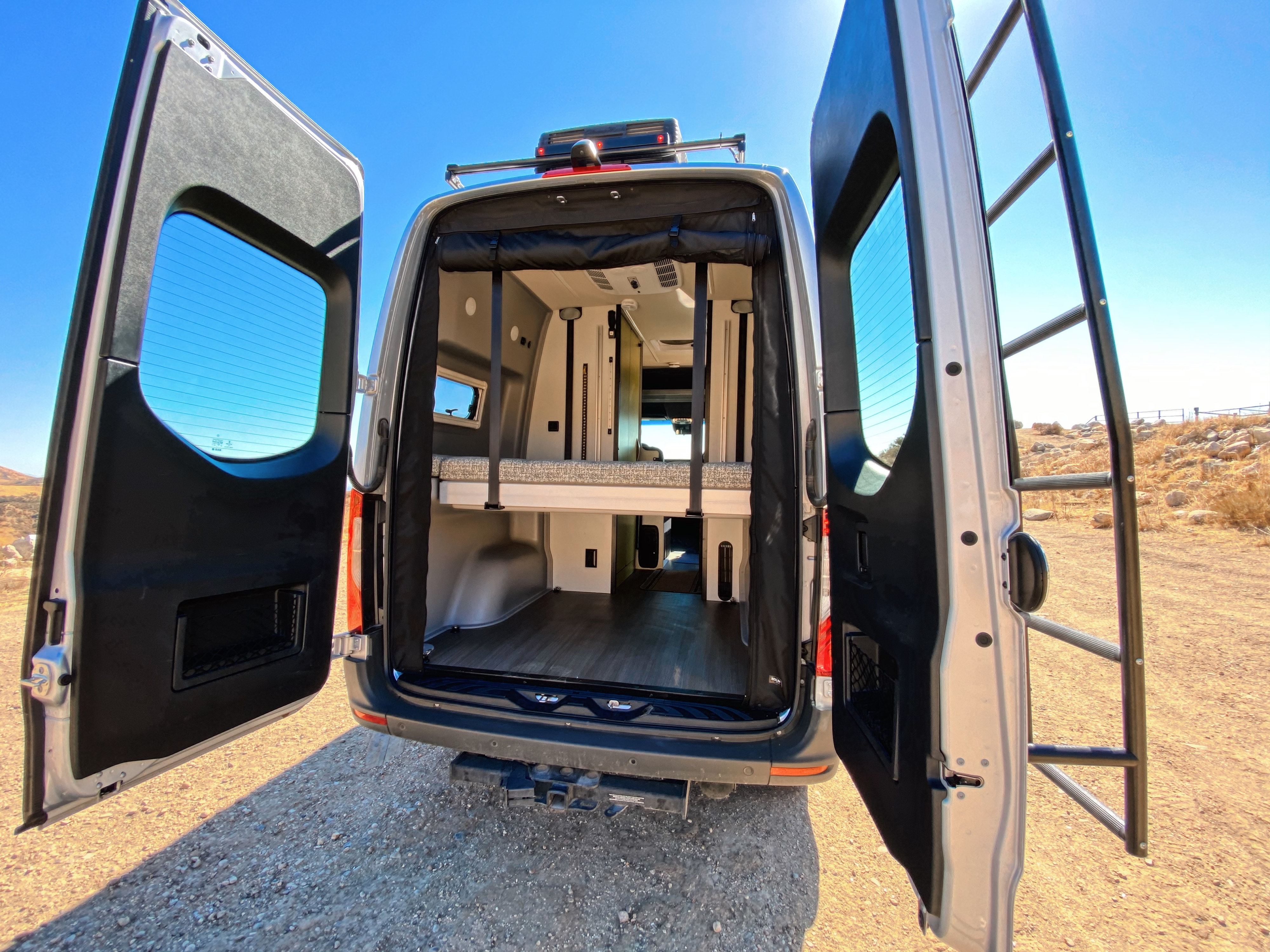 This RV rental's open rear doors showcase a versatile interior with a bunk bed and lower storage. Ready for your next adventure!. Winnebago Revel 2020