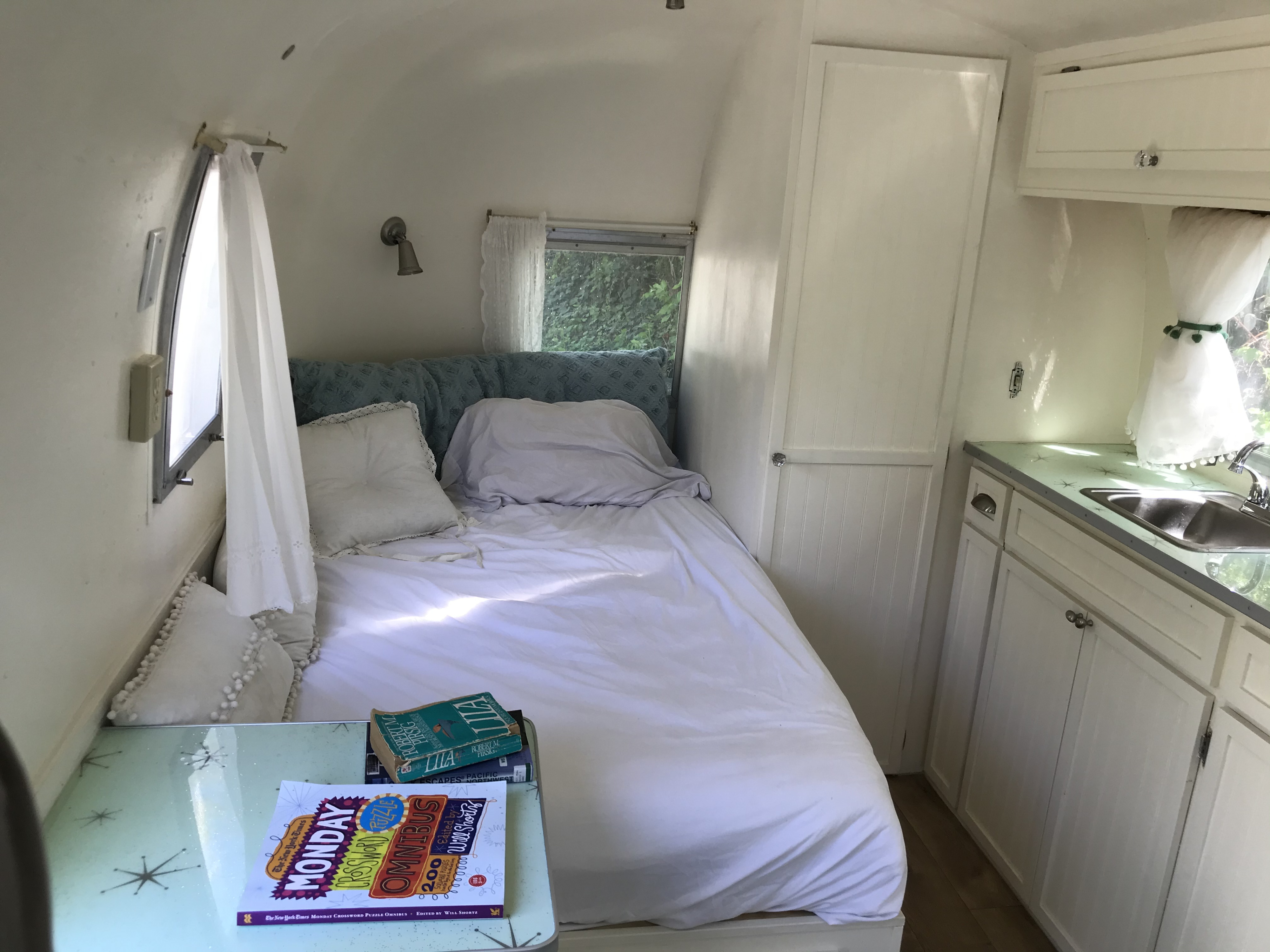 Cozy RV rental interior: a comfortable bed, compact kitchen with vintage green countertop, and storage in this travel trailer.. Airstream Caravel 1968
