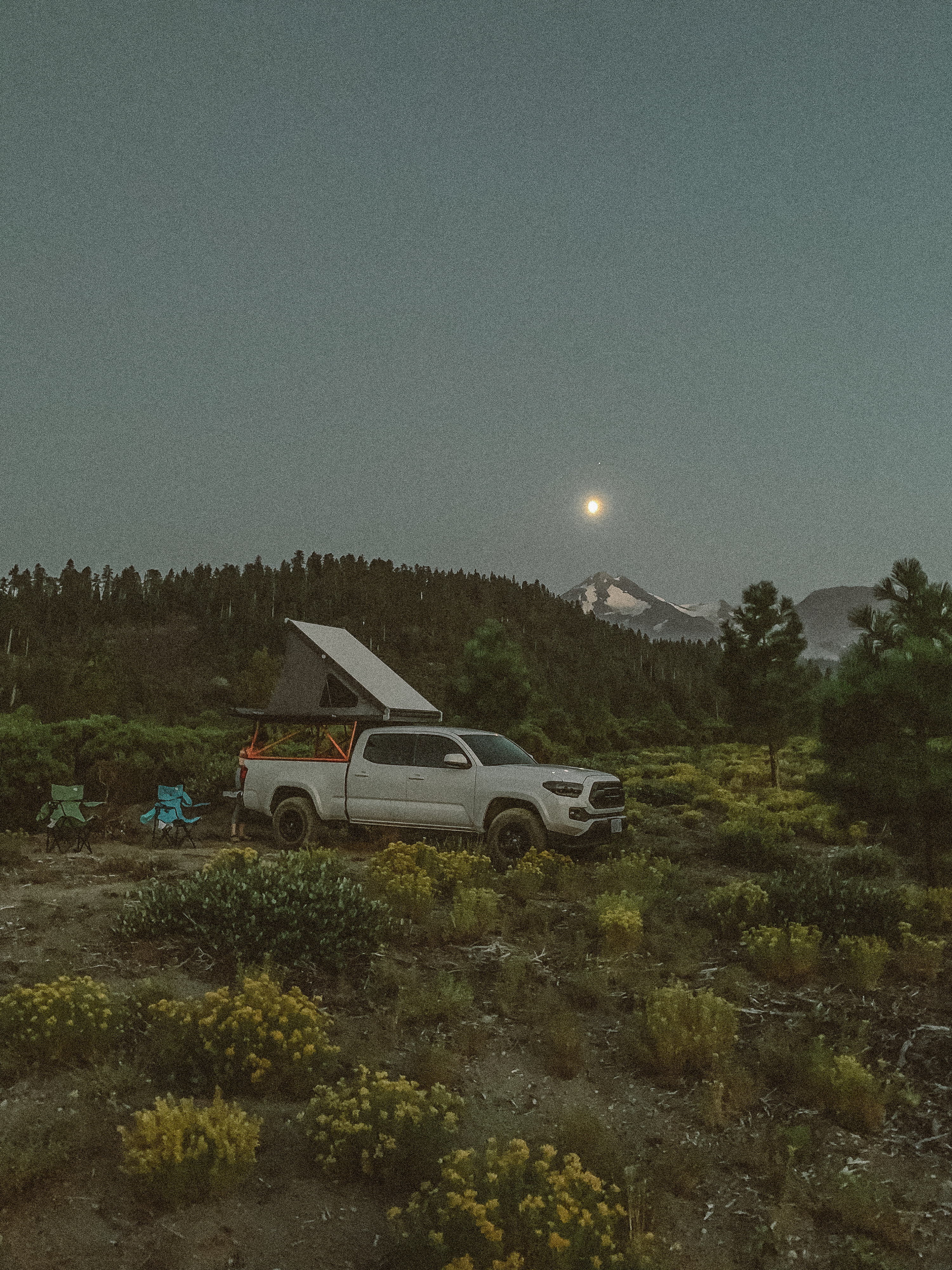 White RV rental truck with roof-top tent open for camping. Moonlit mountains & forest at night, ideal for outdoor adventure.. Other Other 2019