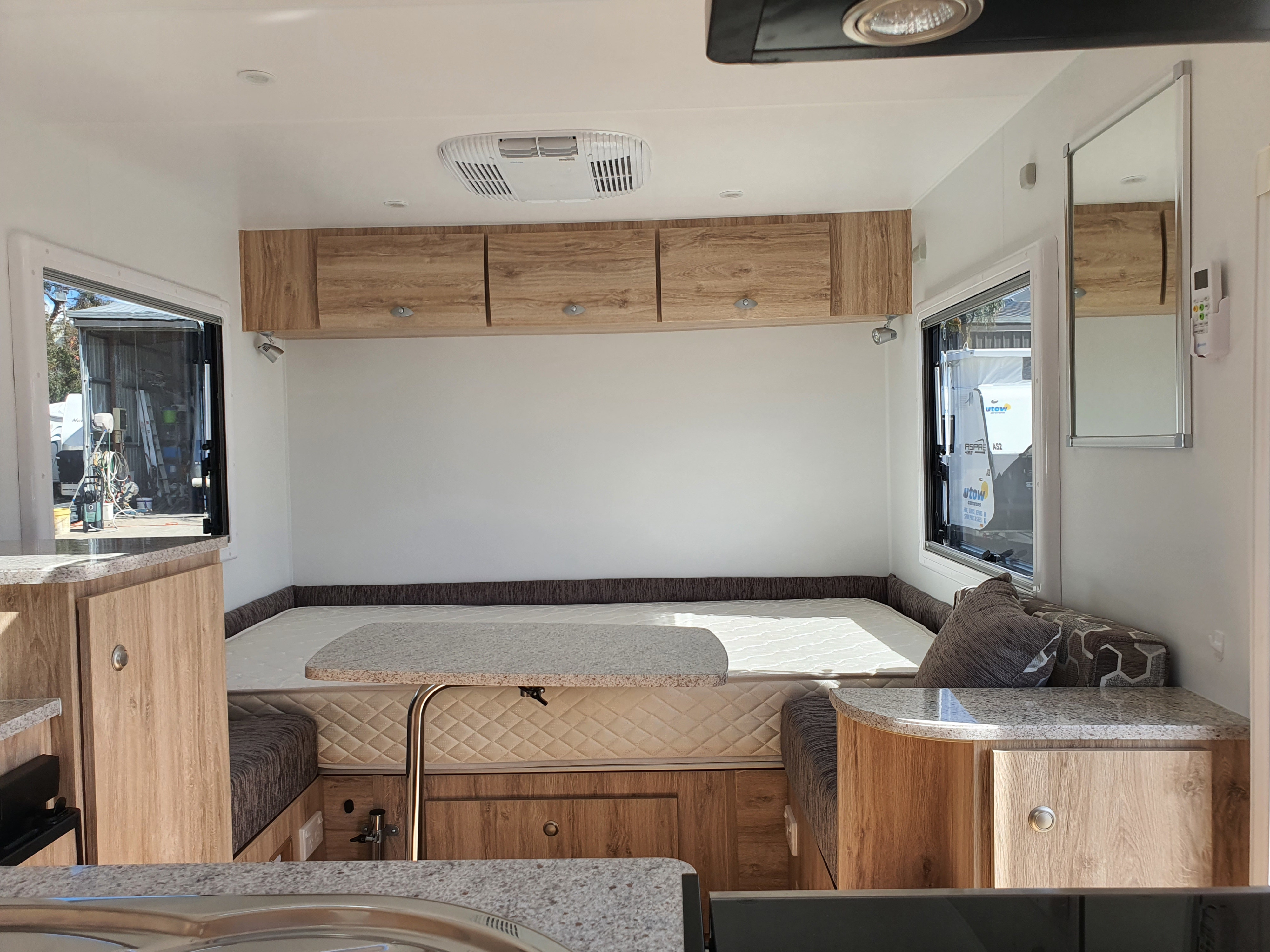 Modern **RV rental** interior showcasing a spacious bed/dinette, wooden overhead cabinets, and a functional kitchen counter.. Avan Aspire 402 2018