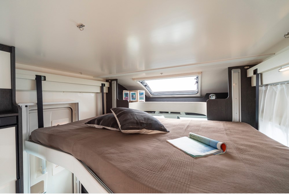 Spacious RV rental bedroom featuring a comfortable, elevated bed and an overhead window, perfect for travel.. Rollerteam Zefiro 696 2025