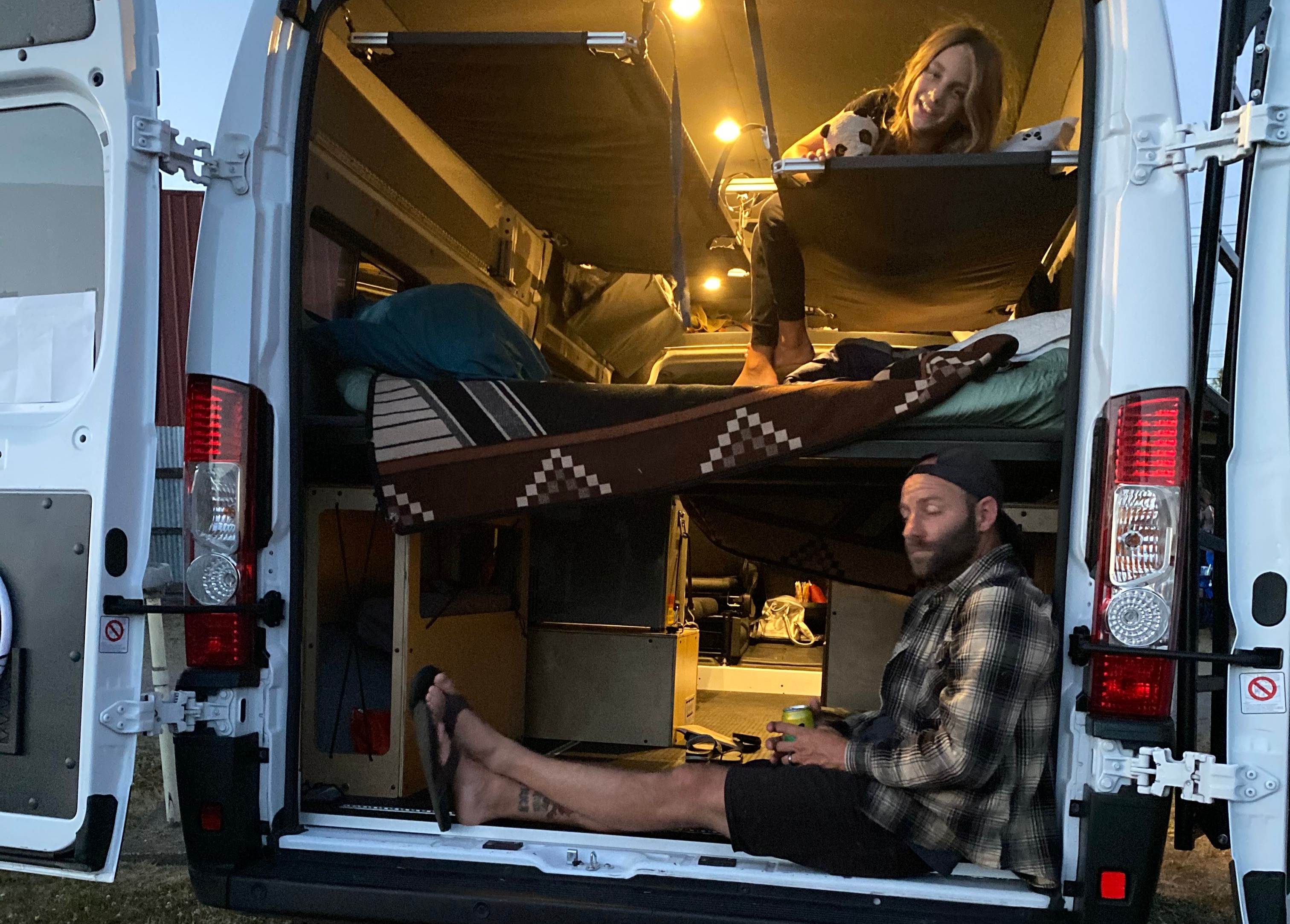 Enjoying a cozy **rv rental** campervan, a man relaxes below while a woman smiles from her bunk. Perfect for van life adventures!. Ram Promaster 2500 2019