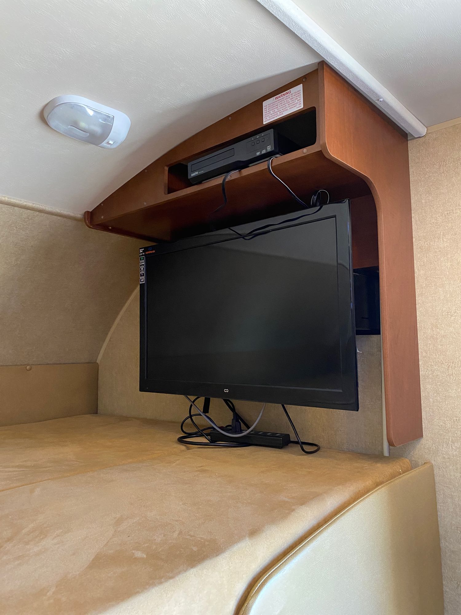 This cozy RV rental interior features an entertainment setup with a TV and DVD player mounted above a comfortable bunk bed.. Jayco Redhawk 2014