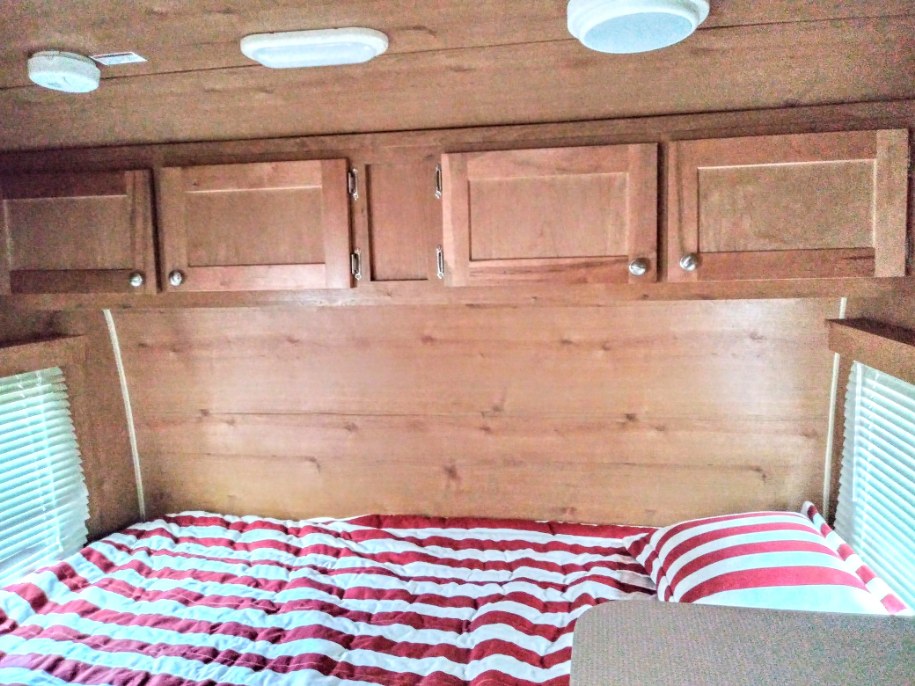 Cozy queen bed with storage above. Riverside RV Retro 2018