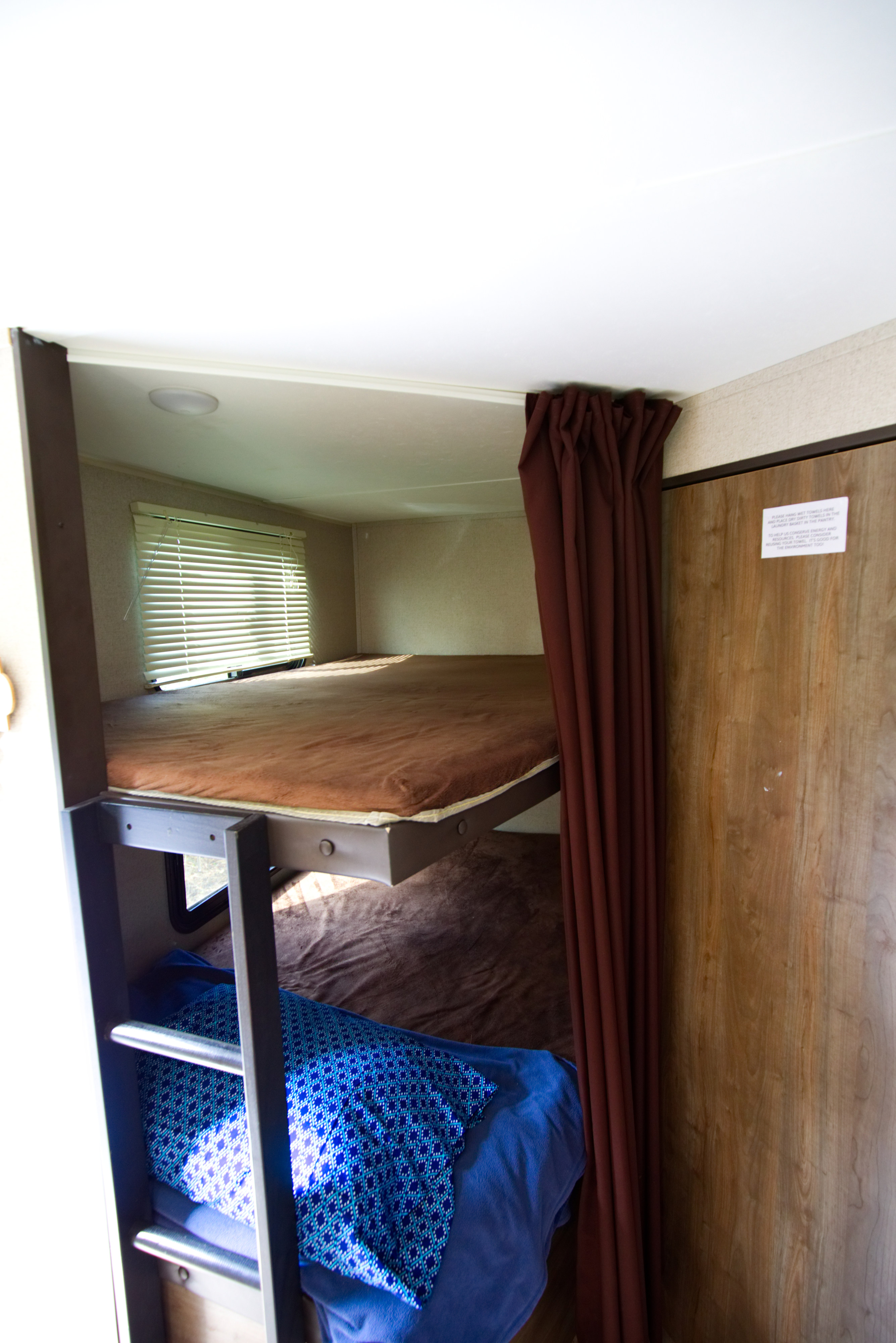 RV rental interior showing cozy bunk beds, a window with blinds, and a privacy curtain for comfortable sleeping.. Other Other 2018
