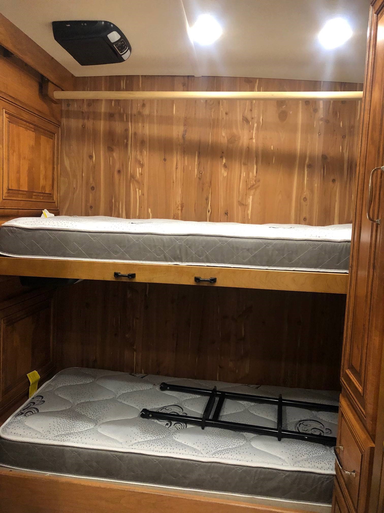 This RV rental features sturdy wooden bunk beds, perfect for extra sleeping space. A ladder is visible on the lower bunk.. American Coach American Dream 2020