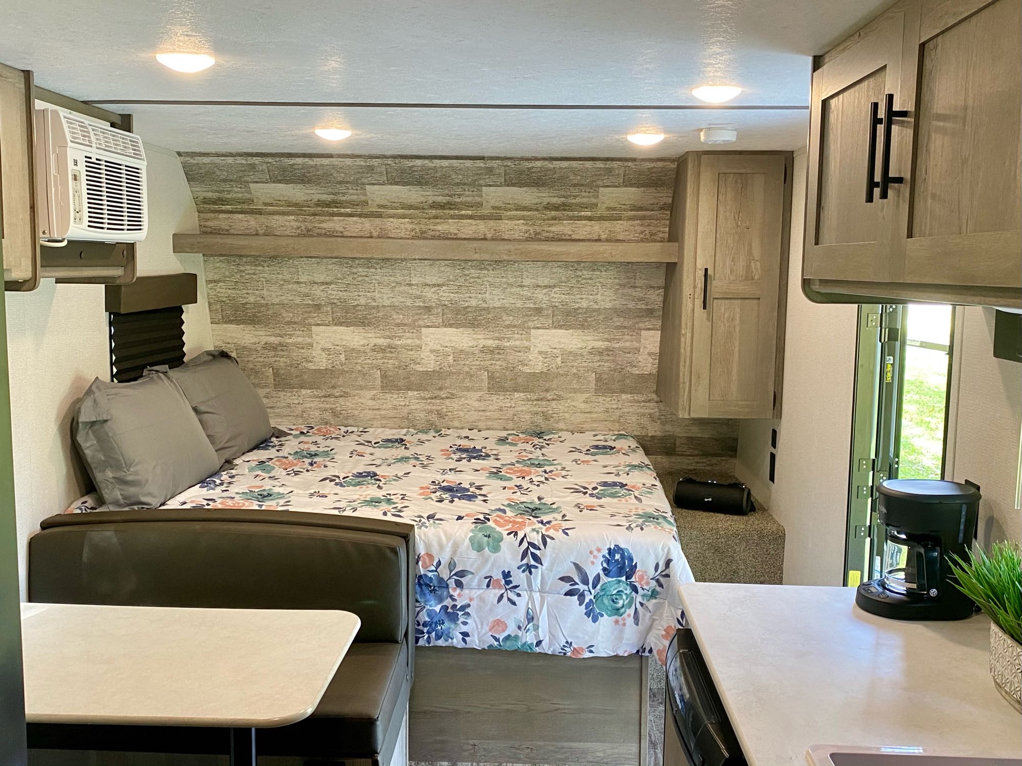 Cozy RV rental interior: floral bed, dinette, AC unit, and coffee maker. Ready for your next adventure.. Keystone RV Springdale 2021
