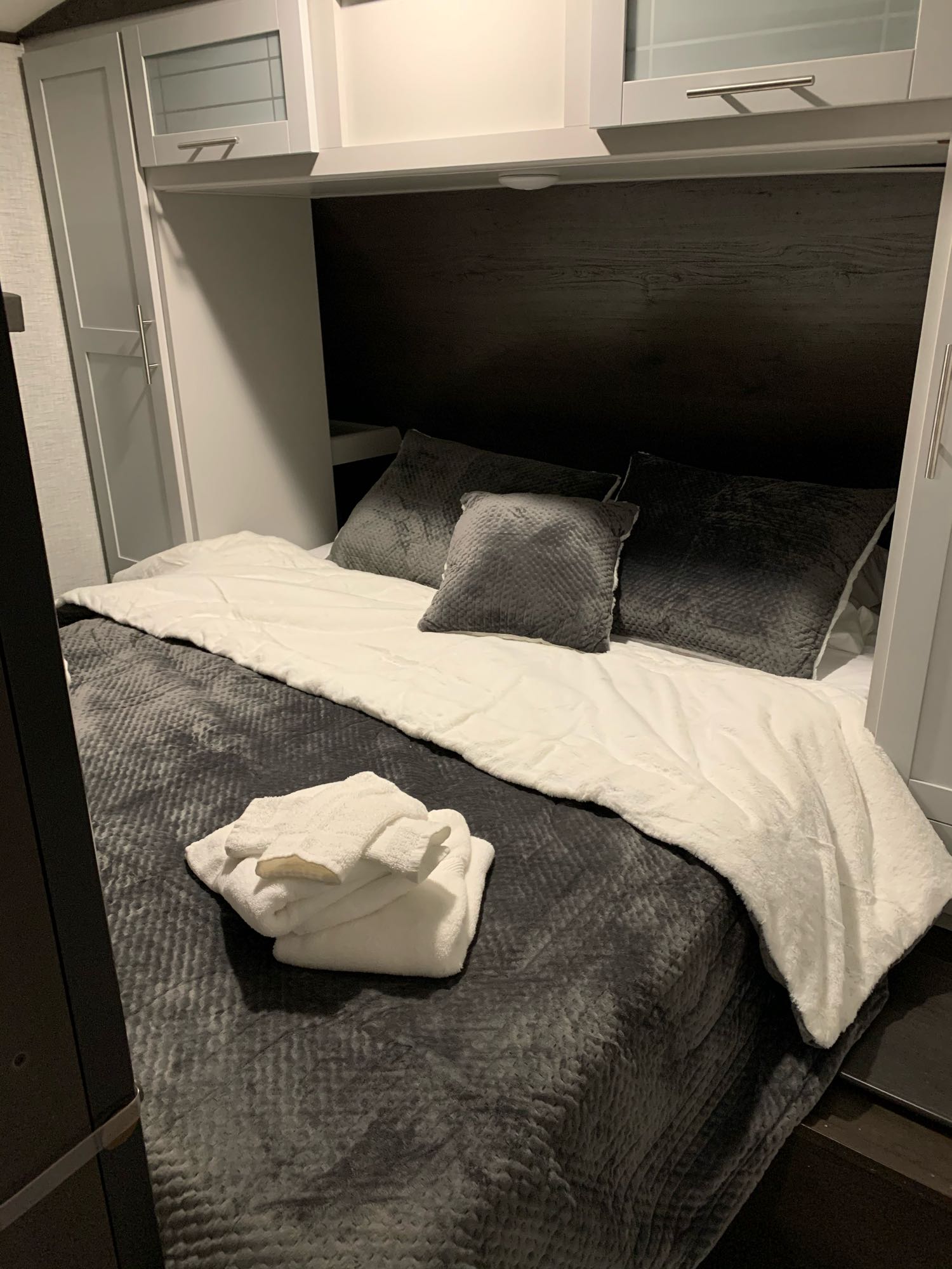 Clean, inviting bed setup inside an RV rental, featuring grey/white bedding & folded towels. Ready for your adventure.. Keystone RV Bullet Ultra Lite 2021