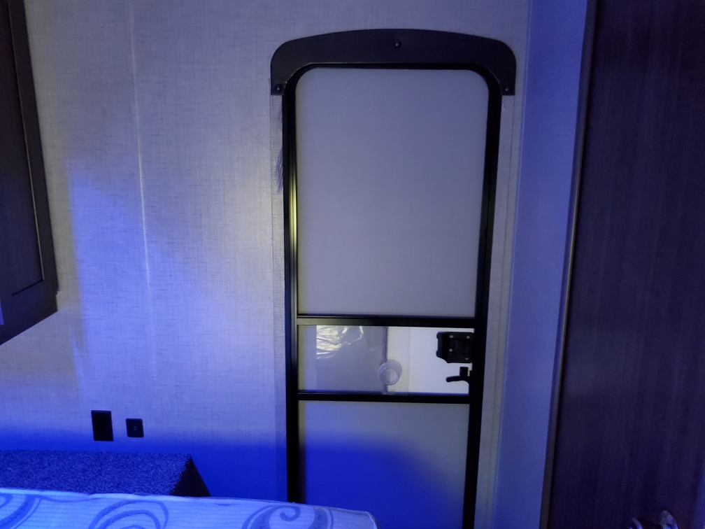 Cozy RV rental interior featuring a white door, blue-lit wall, power outlets, and a comfortable bed setup.. Crossroads Zinger 2018