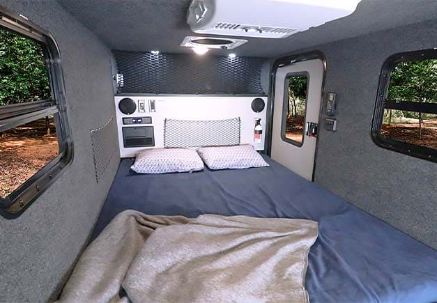 Spacious RV rental bedroom with comfortable bed, windows, and controls. Enjoy nature from inside.. InTech RV InTech RV Trailer 2020