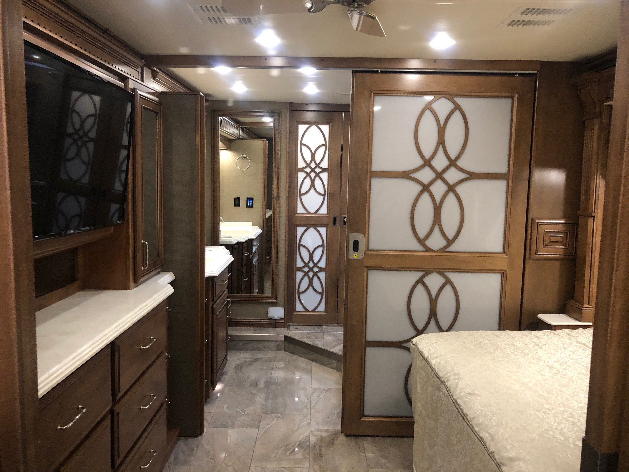 RV rental: a luxury motorhome master suite featuring a bed, full vanity, elegant wood cabinetry, and a TV setup.. Monaco Signature 2020