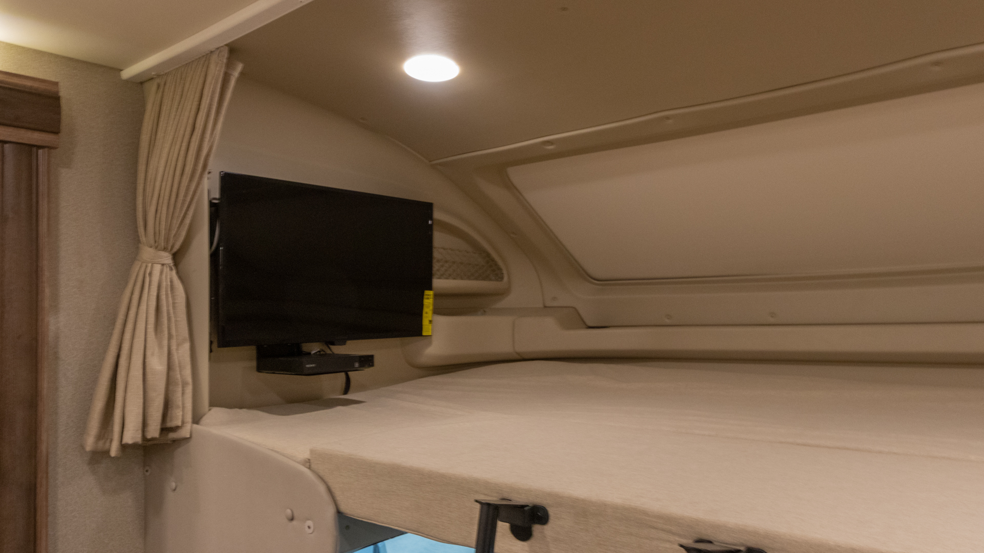 Visually, this RV rental shows a bunk bed, mounted TV, and tied-back curtains in a cozy interior space.. Jayco Greyhawk prestige 30XP 2020