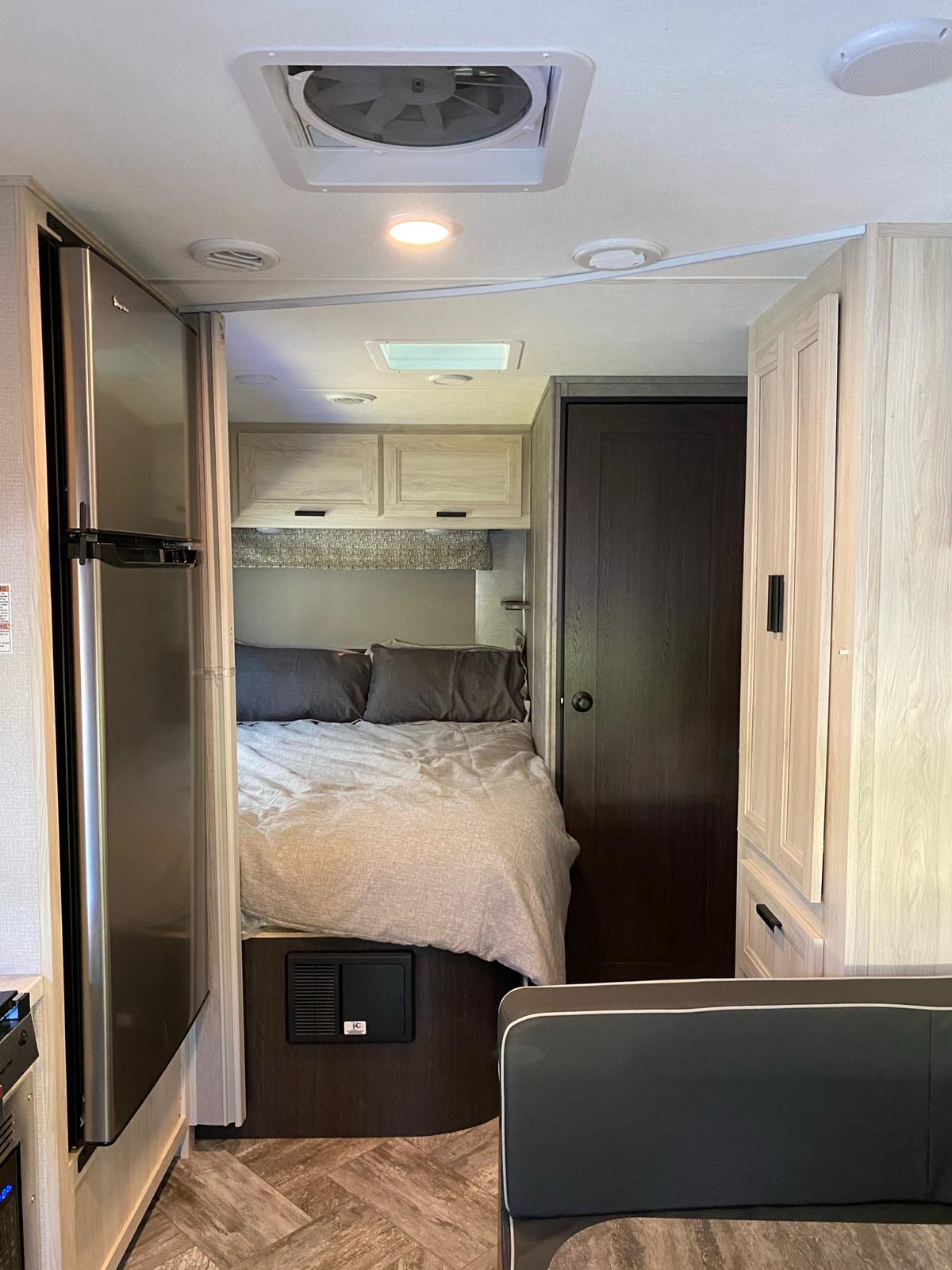 RV rental interior featuring a bedroom, refrigerator, and dinette. Functional and compact.. Forest River Forester 2021