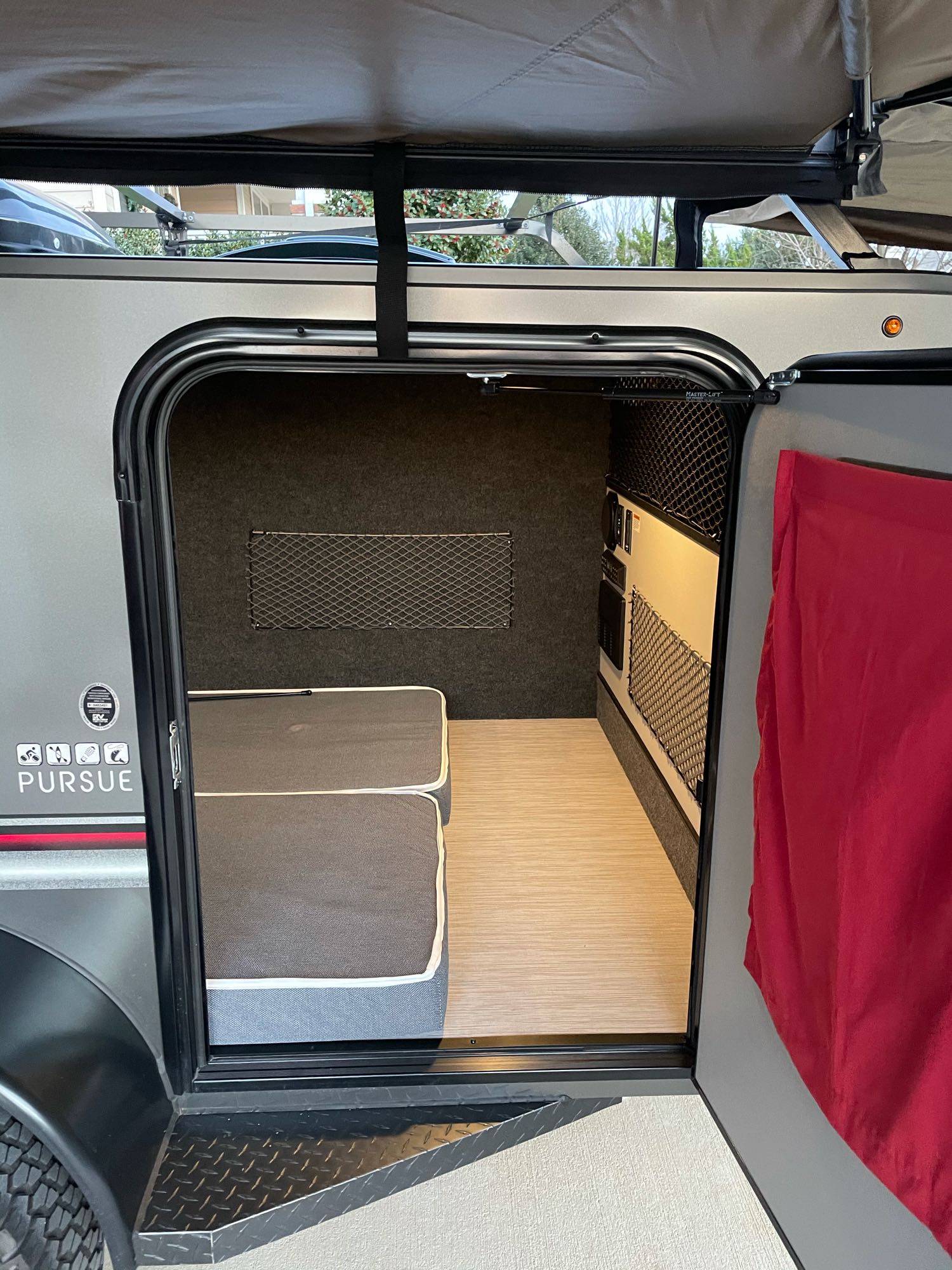 Step into this compact RV rental, featuring a cozy bed, light floor, and utility wall with mesh storage. Perfect for adventures.. InTech RV InTech RV Trailer 2020