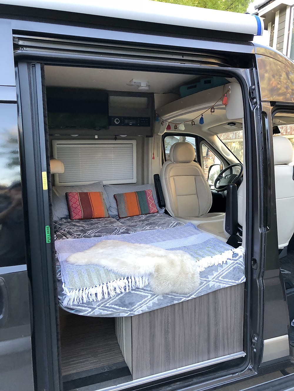 Inside a comfortable RV rental: a plush bed, entertainment system, and swivel front seats, perfect for van life travel.. Winnebago Travato GL 2019