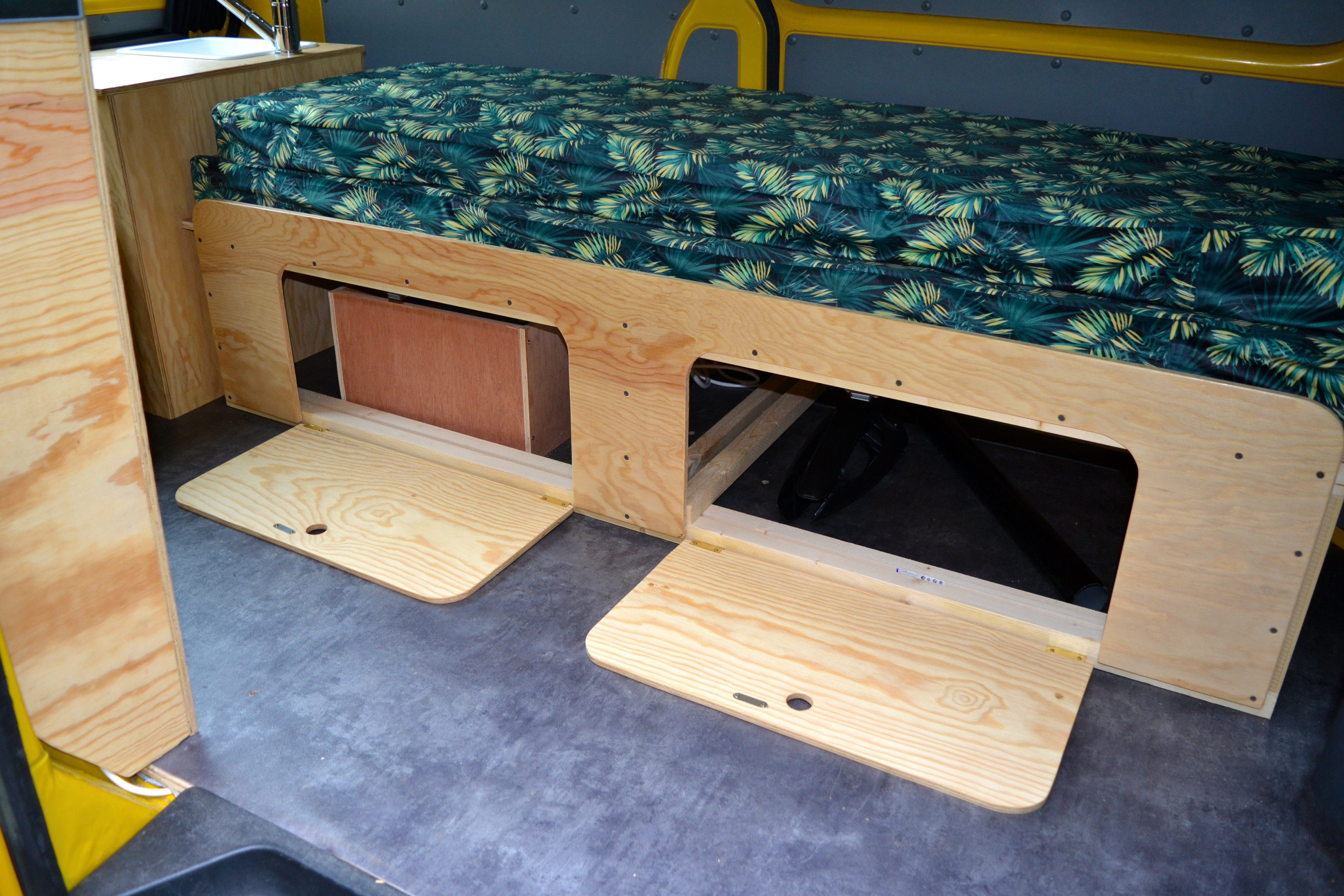 RV rental interior: Custom wood bed with tropical mattress, under-bed storage, and compact sink unit.. Volkswagen Transporter T5 2012