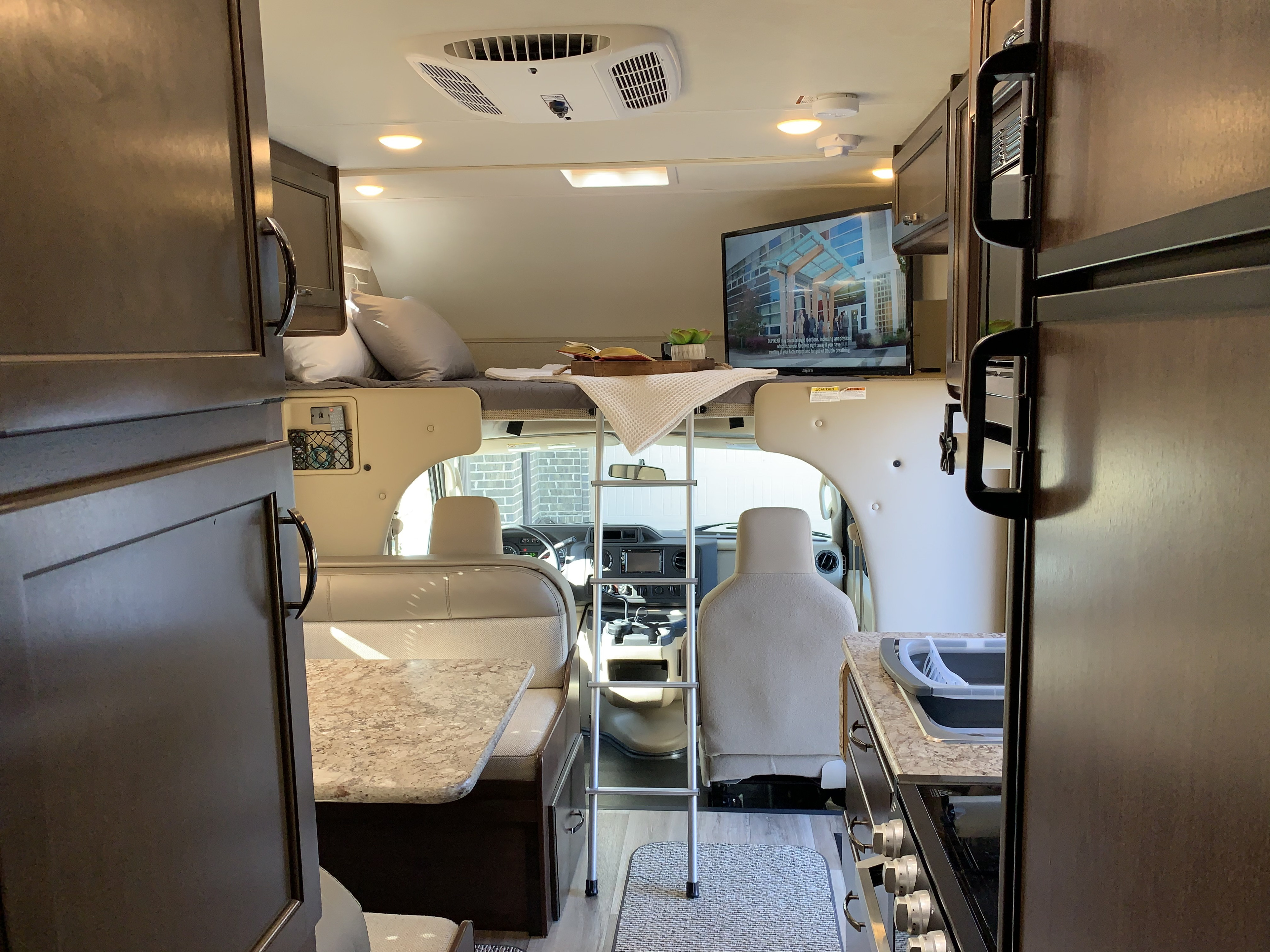Spacious RV rental interior featuring a cab-over bed, dinette, kitchen, and front cockpit view.. Thor Freedom Elite 2019