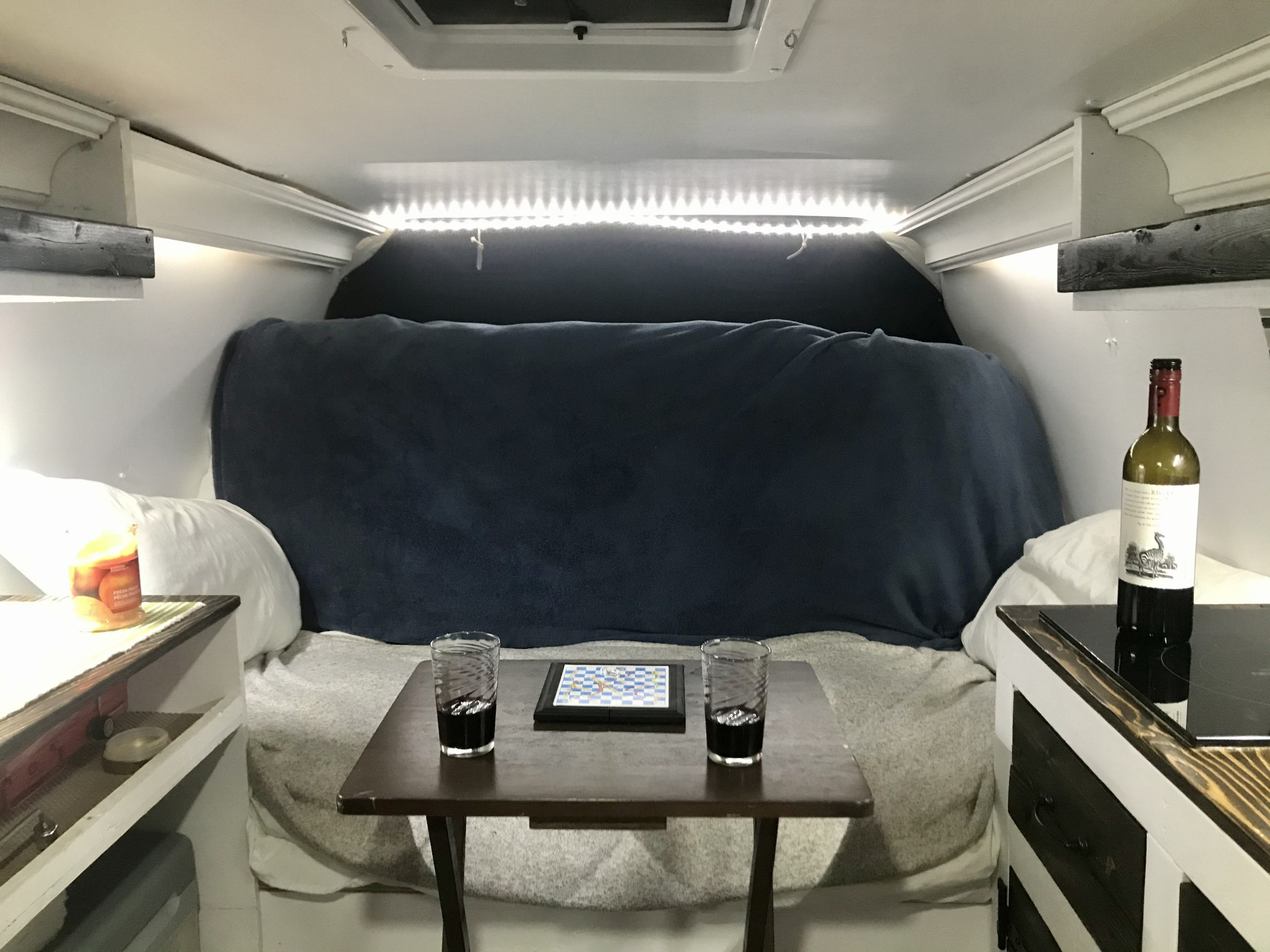 An RV rental's inviting interior: bed, game, wine, and soft LED lighting create a comfortable retreat.. Chevrolet Express Extended 2007