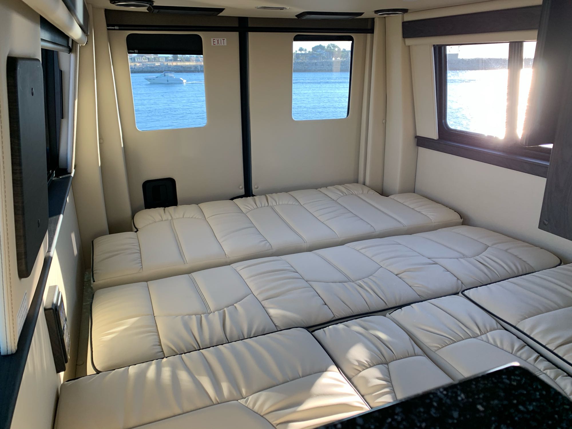 Comfortable rv rental interior featuring convertible beds, bright windows with a scenic water and boat view.. Midwest Automotive Designs Midwest Automotive Designs Class B 2021
