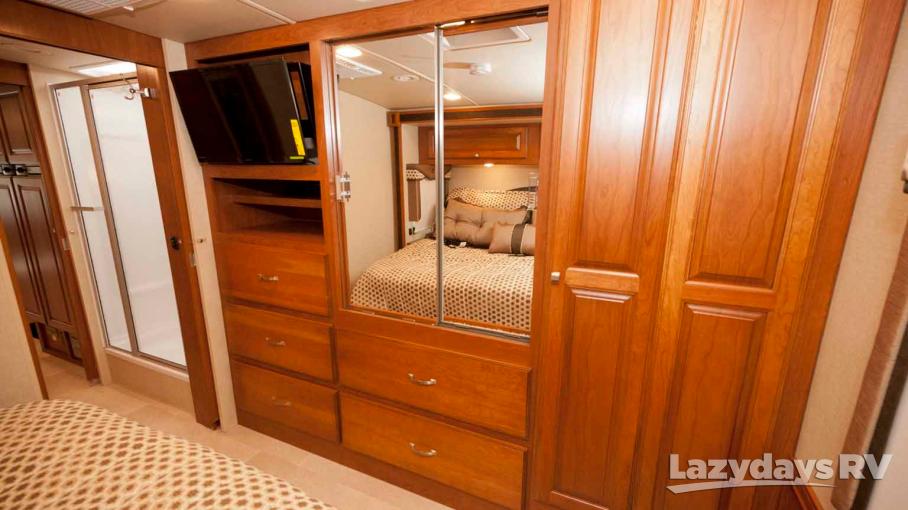 Inside this **rv rental**'s bedroom, find a mirrored wardrobe, mounted TV, dresser, and adjacent shower. Smart storage!. Winnebago Sightseer 2015