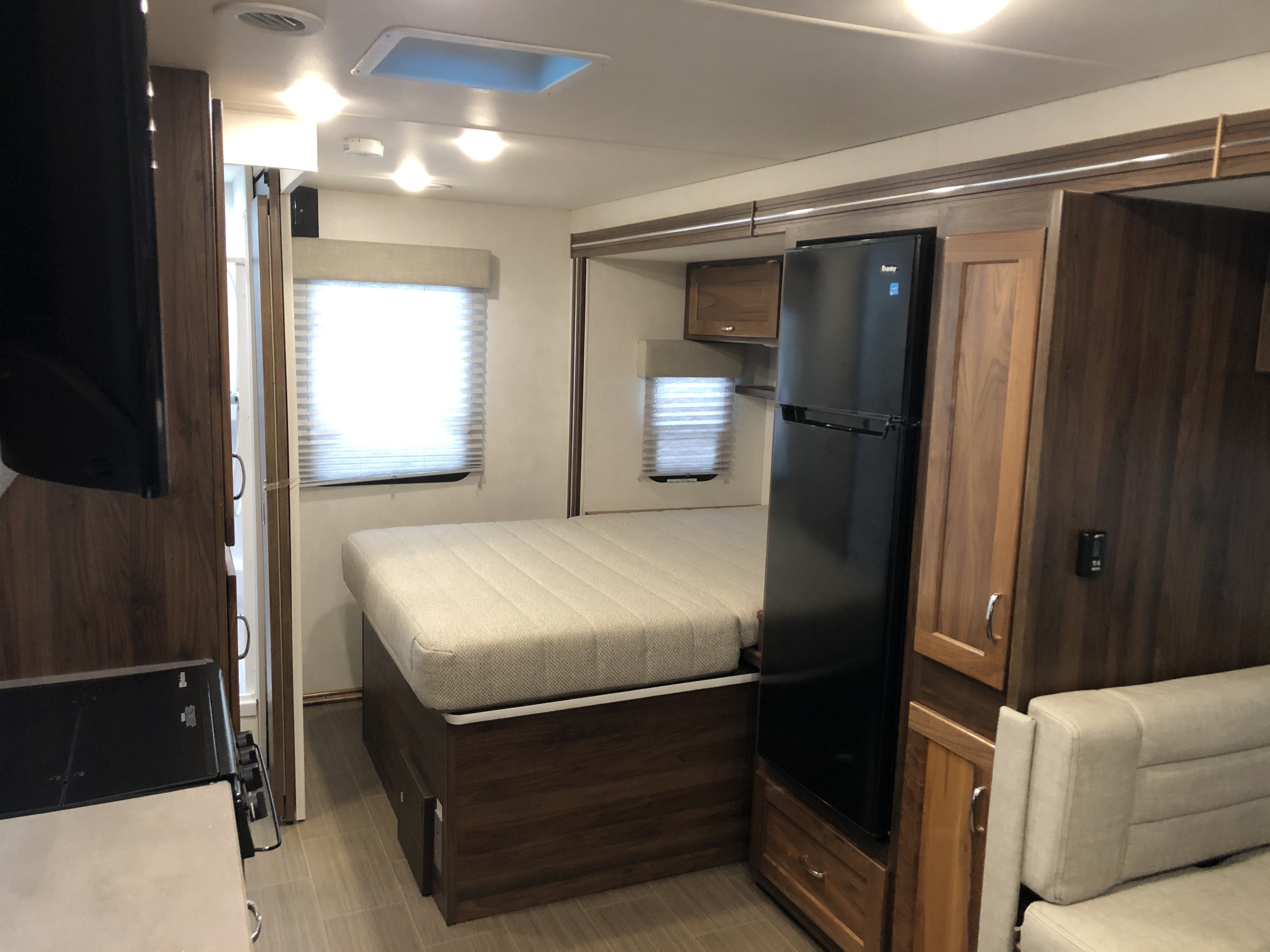 Inside an RV rental: features a comfortable bed, large refrigerator, and spacious living area with light-filled windows.. Winnebago Mercedes Sprinter 2020