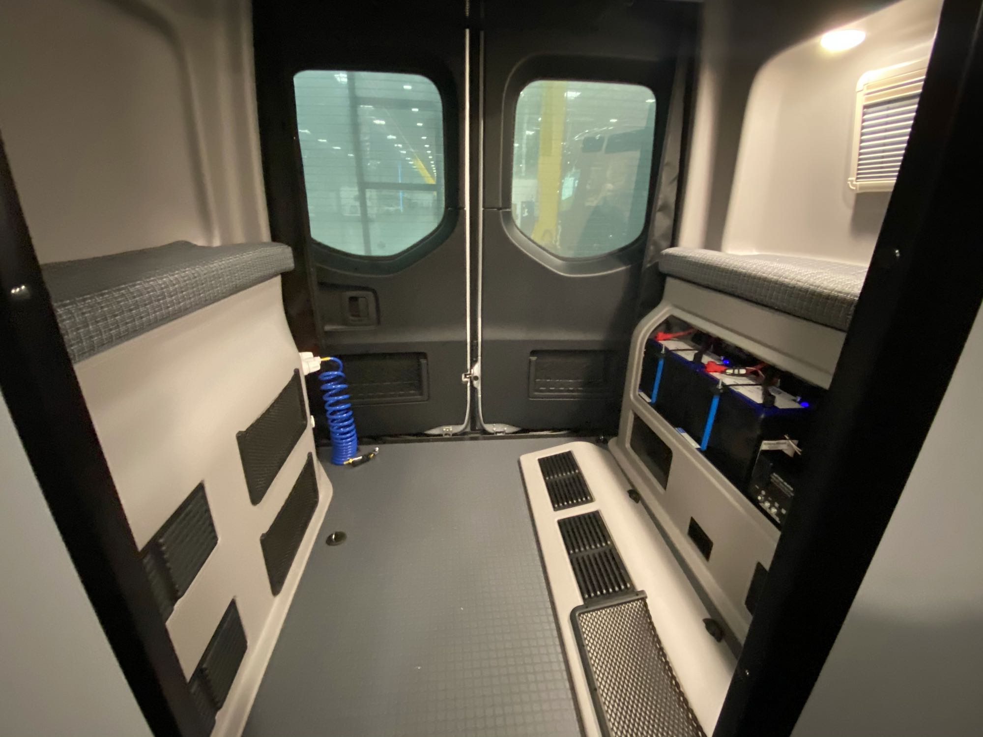 Spacious RV rental van interior featuring cushioned benches, visible power system, and floor ventilation.. Winnebago Revel 2021