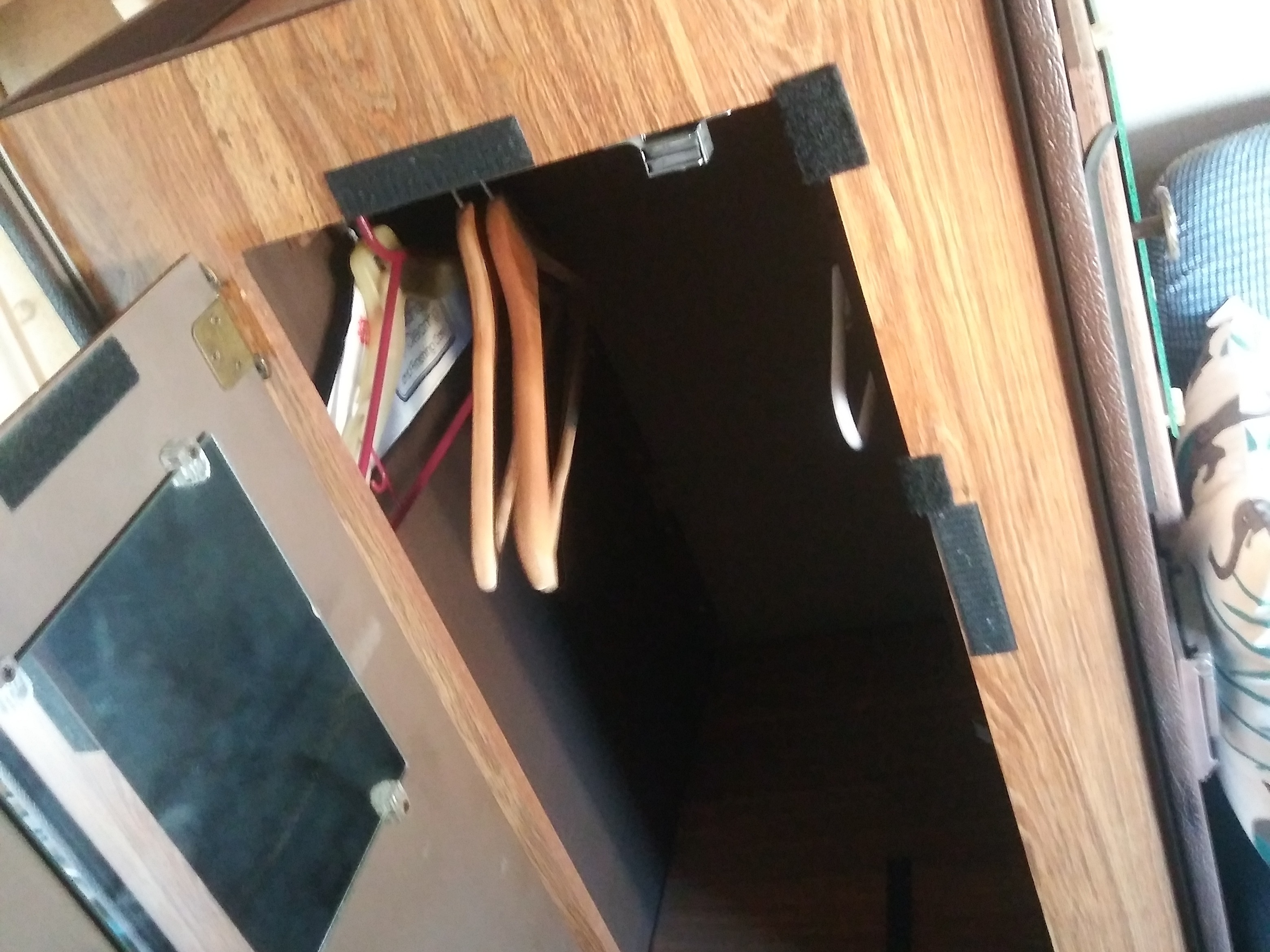 An open, compact wardrobe inside an RV rental, featuring hangers, velcro, and a mirror on the door.. Ford Other 1986